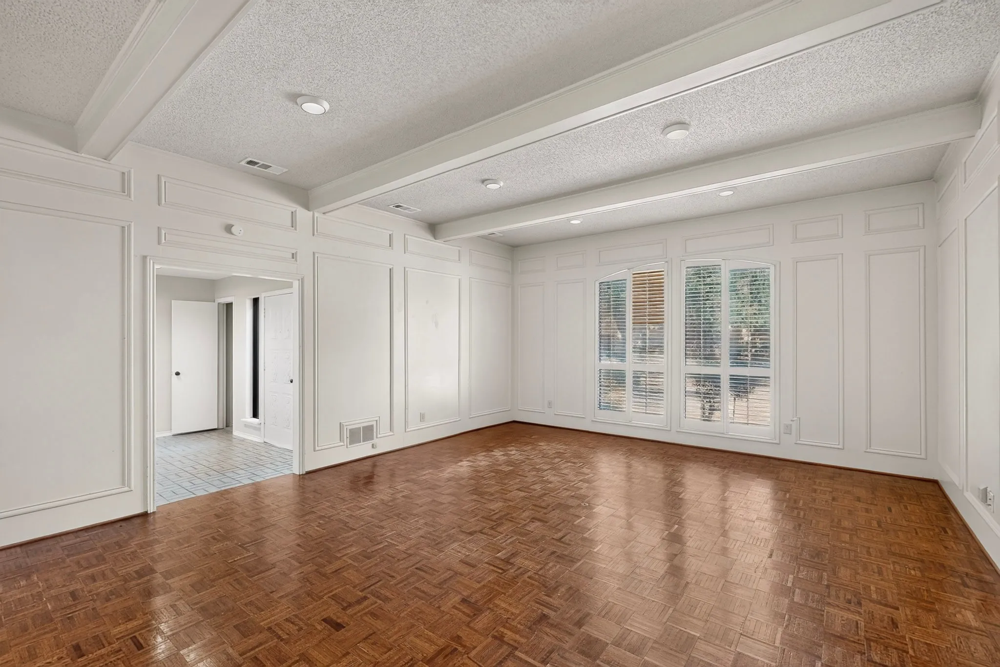 Wall paneling with decorative trim, wood-finish flooring, coffered ceiling, recessed lighting, and large windows
