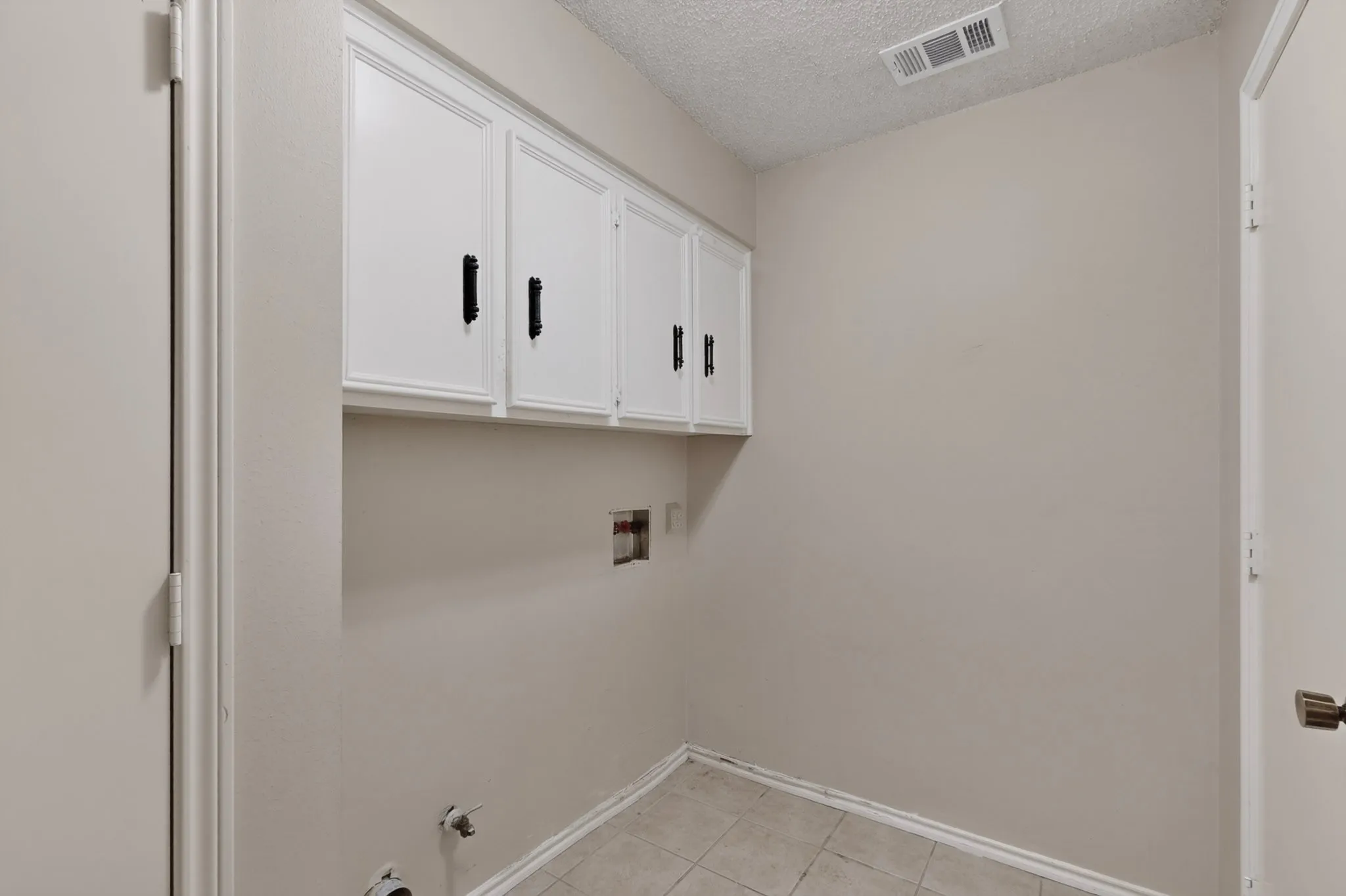 White cabinetry with black hardware, tile flooring, and light neutral wall paint
