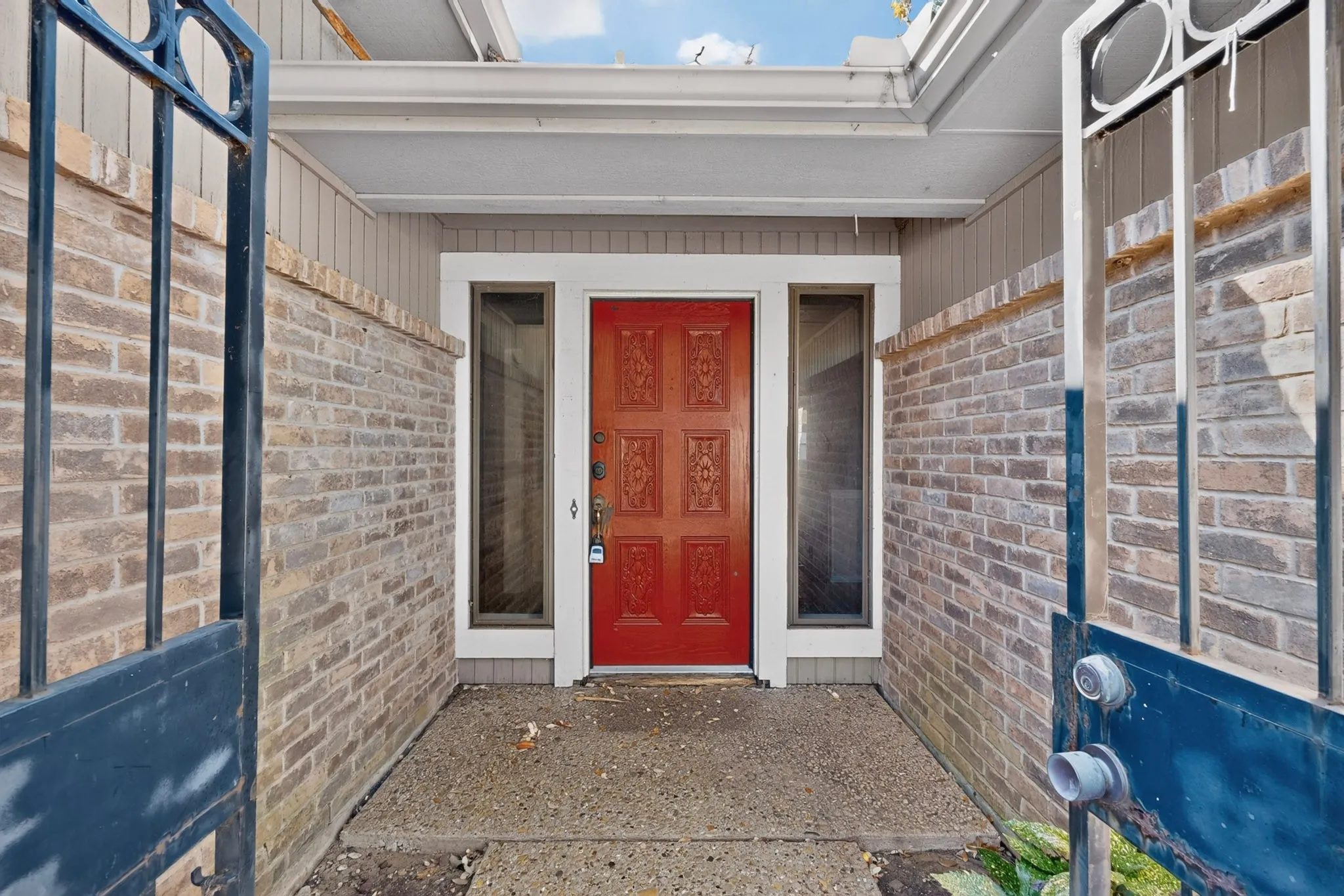 Covered entry with decorative iron gate and brick enclosure