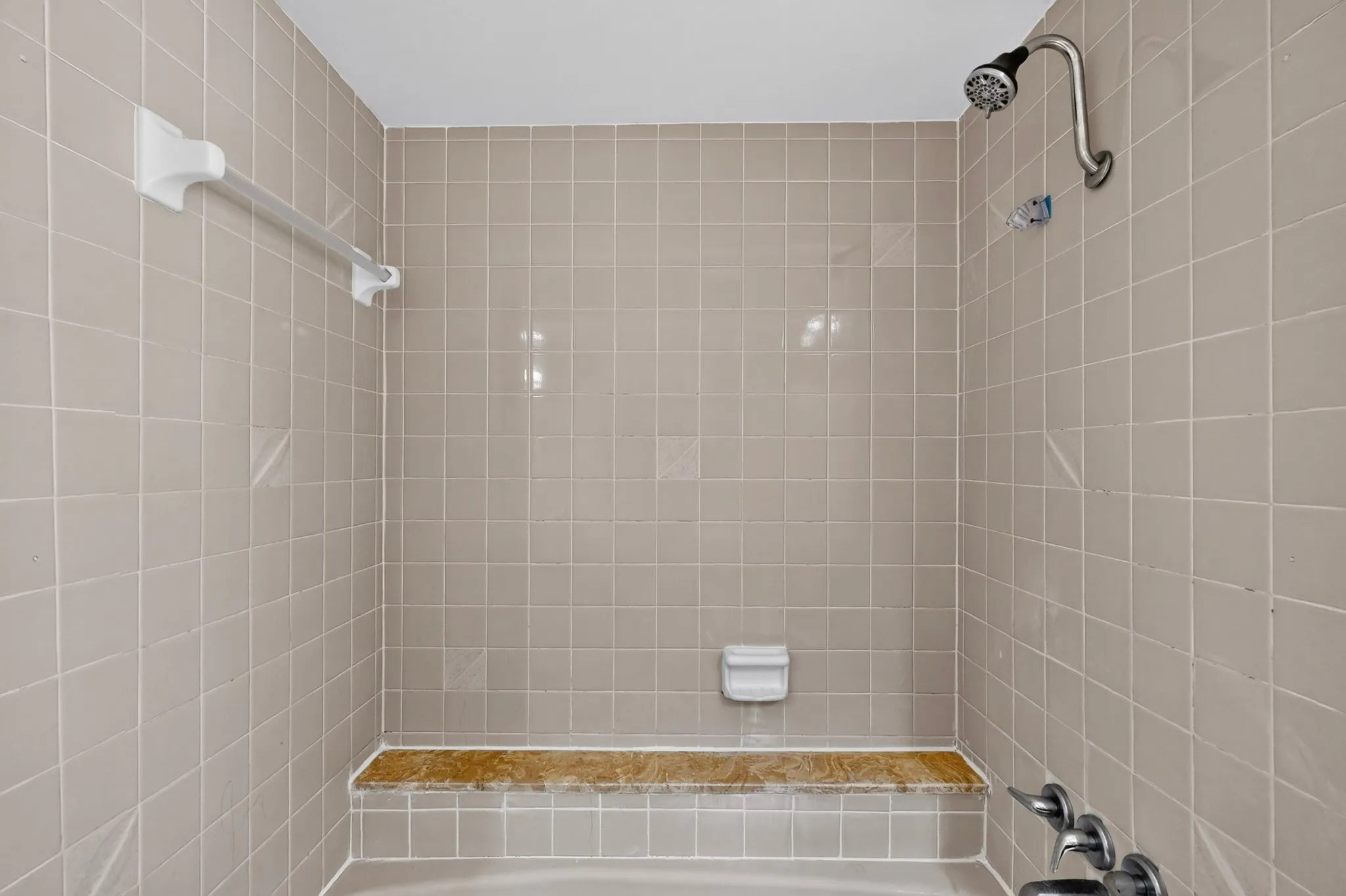 Tiled shower surround with an integrated shower bench and a chrome shower fixture