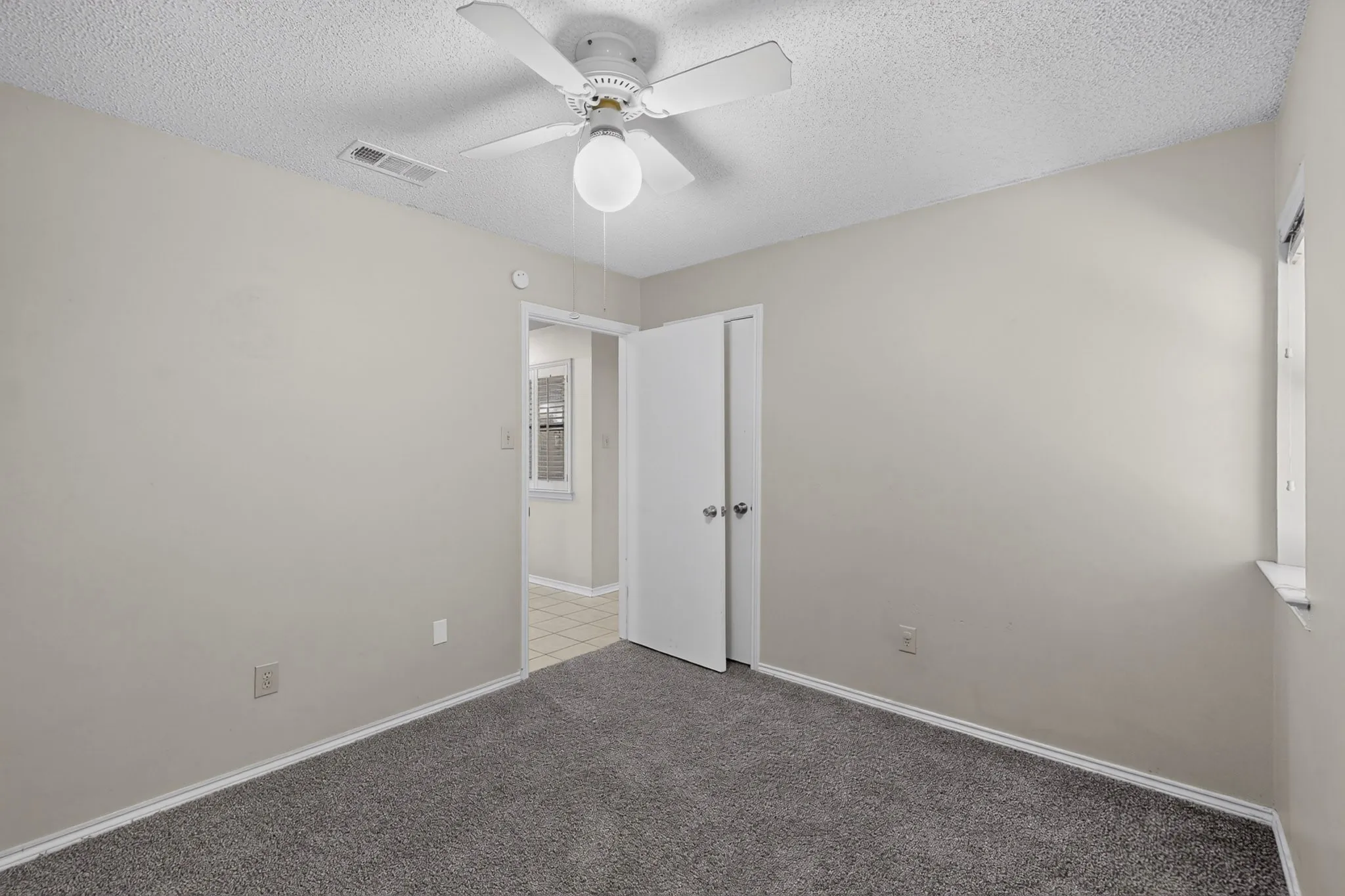 Wall-to-wall carpeting, ceiling fan, and window