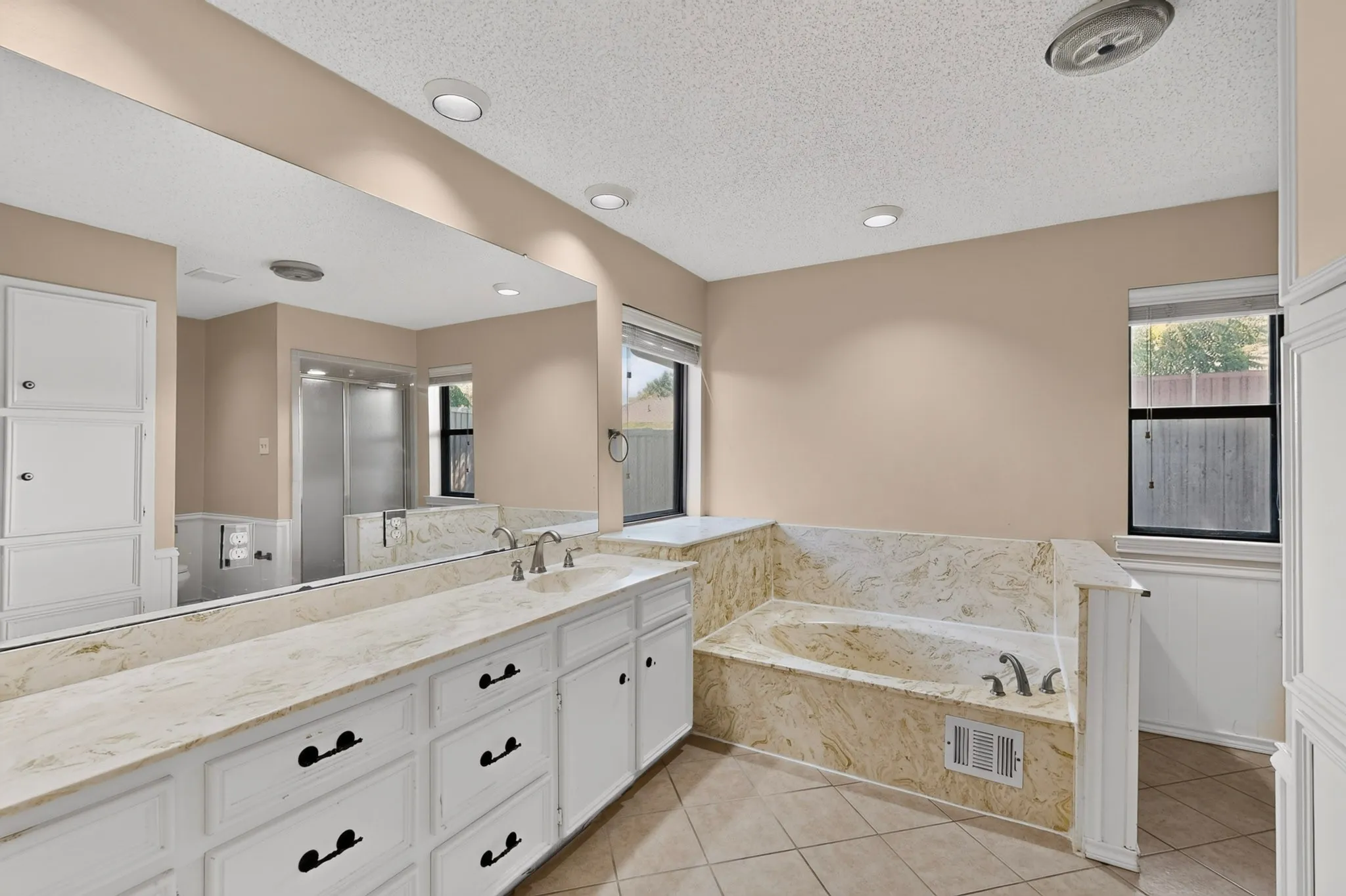 Expansive vanity with dual undermount sinks, stone-finish countertop, and full-wall mirror