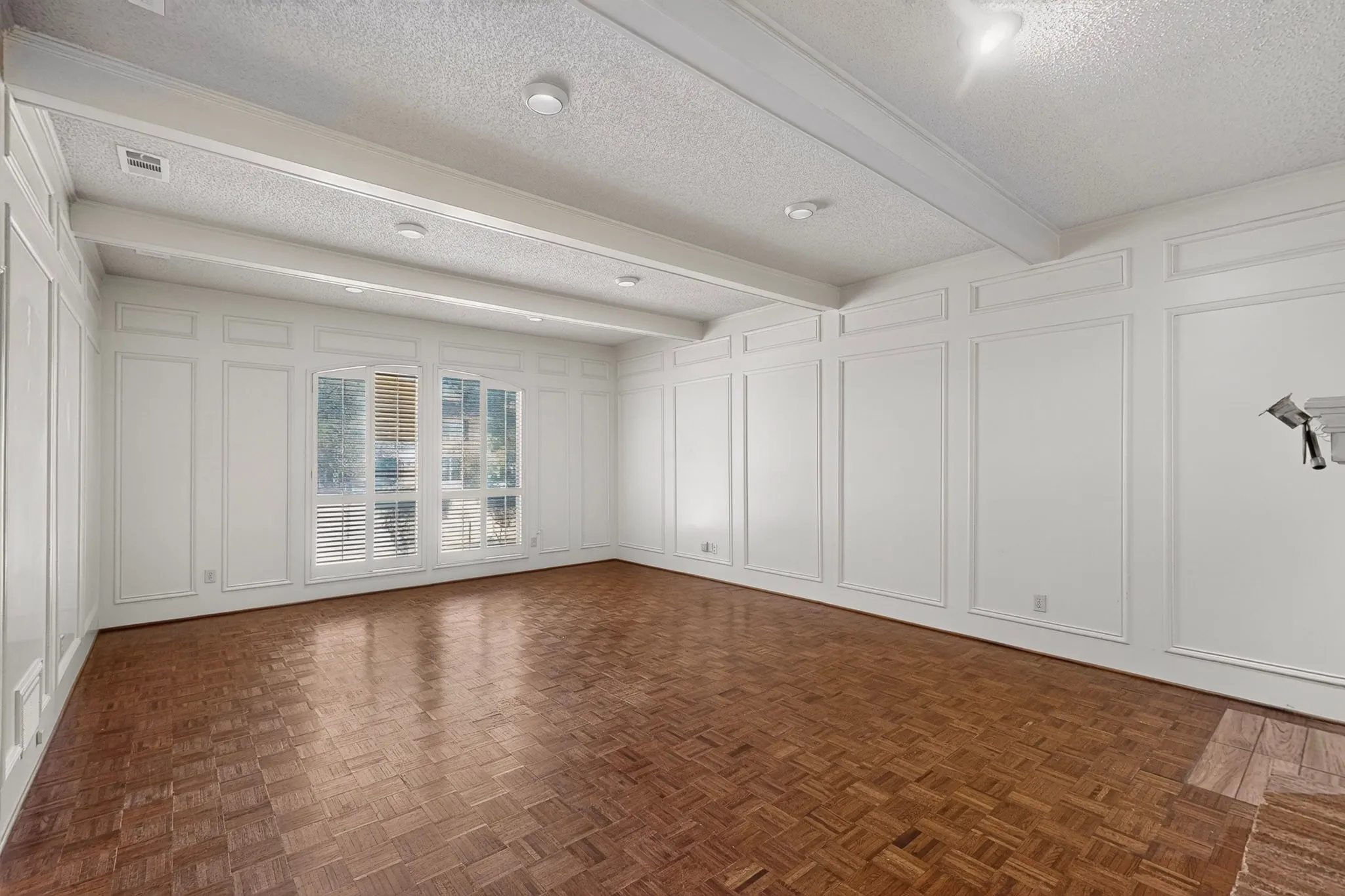 Parquet wood-finish flooring, recessed lighting, decorative wall paneling, and a beamed ceiling