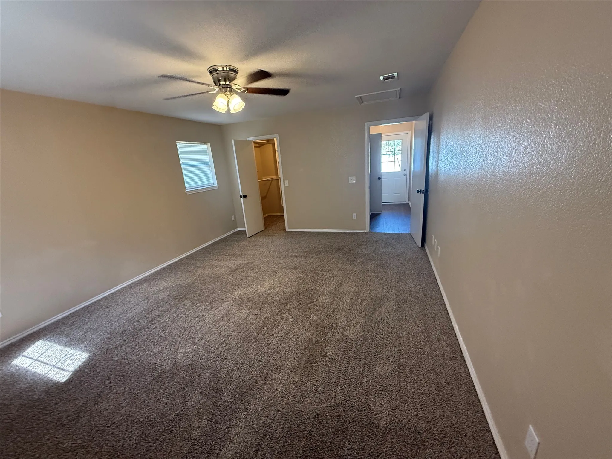 Spacious room featuring carpeting, a ceiling fan with integrated lighting, and a closet with a bifold door