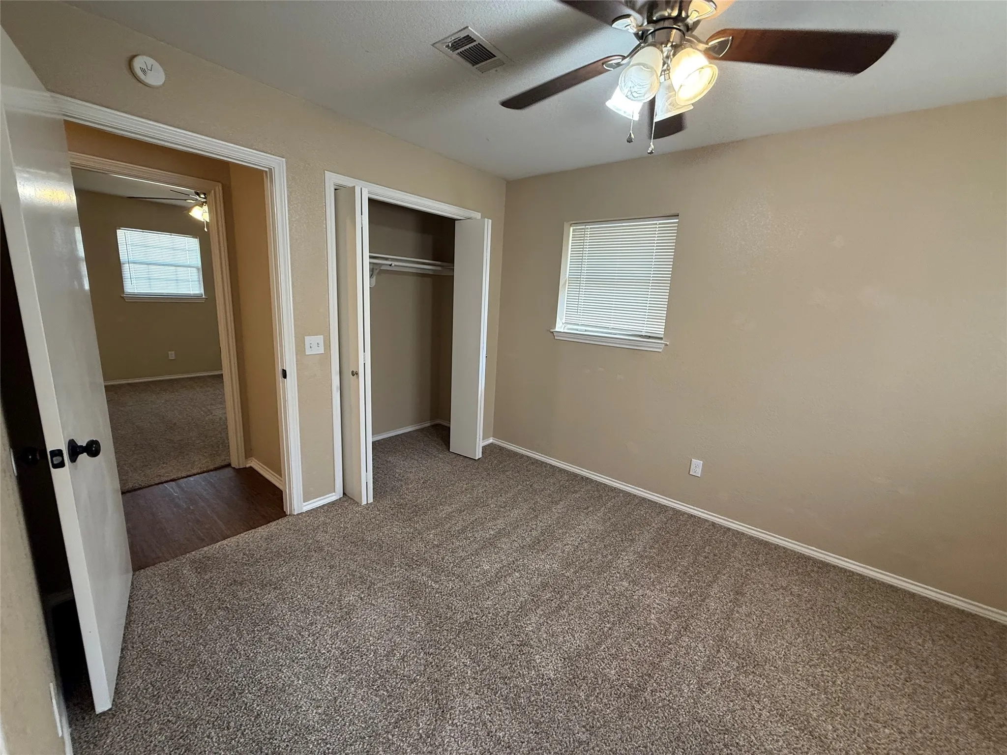 Carpeted flooring, ceiling fan with integrated lighting, window with blinds, and built-in closet with hanging rod