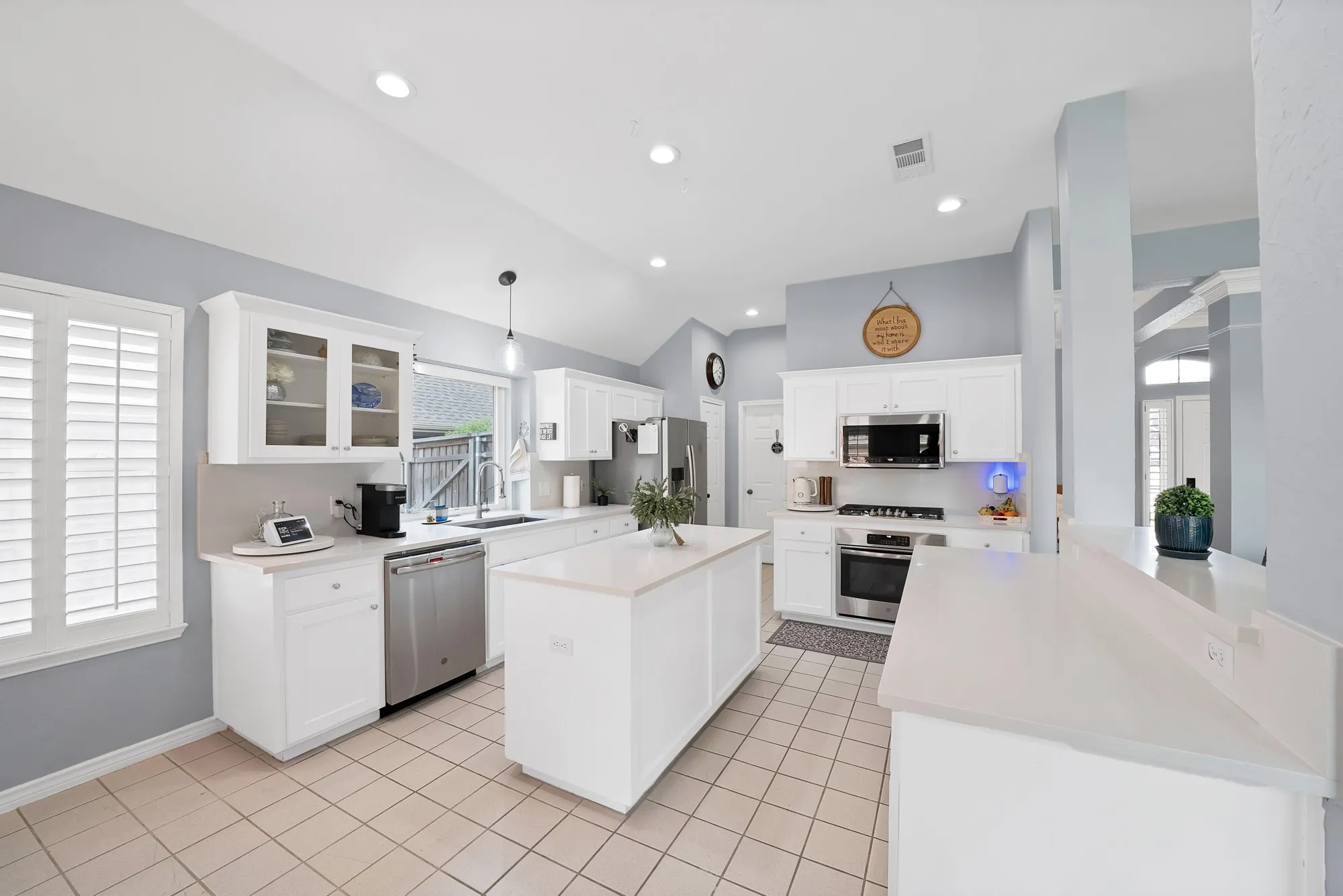 Kitchen featuring vaulted ceilings, recessed lighting, white cabinetry, a central island, and stainless steel appliances
