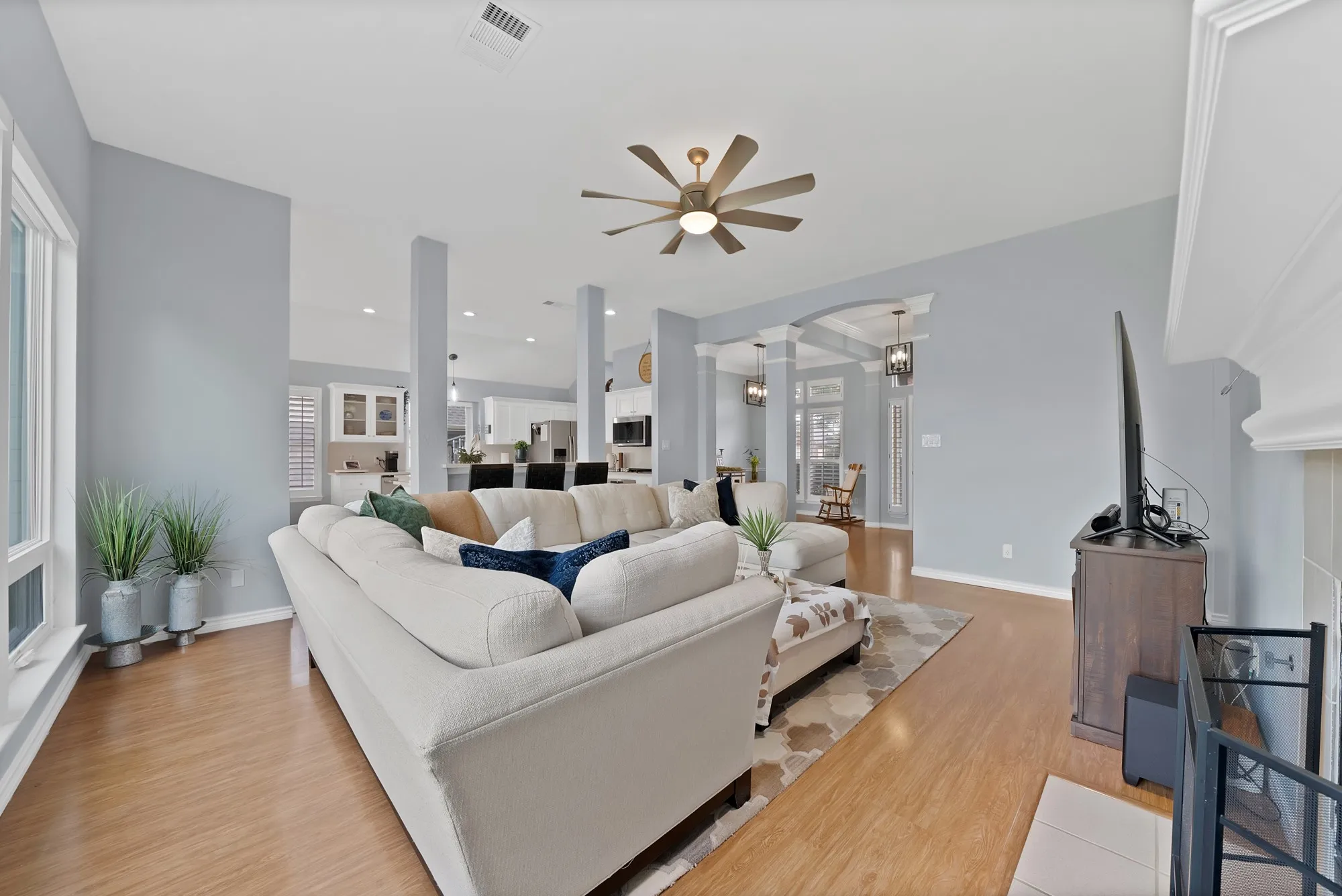 Spacious living area with wood-finish flooring, ceiling fan, and decorative archways