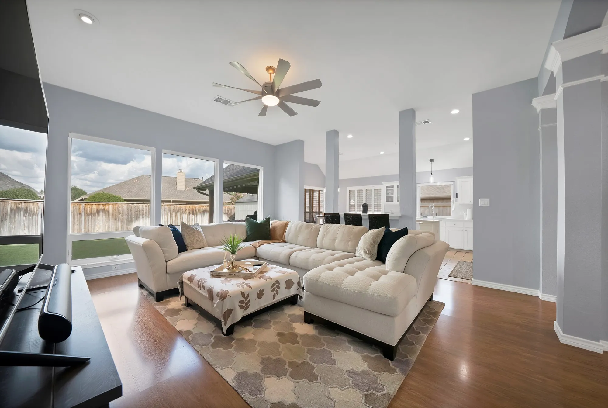 Recessed lighting, wood-finish flooring, ceiling fan, expansive windows, and architectural columns