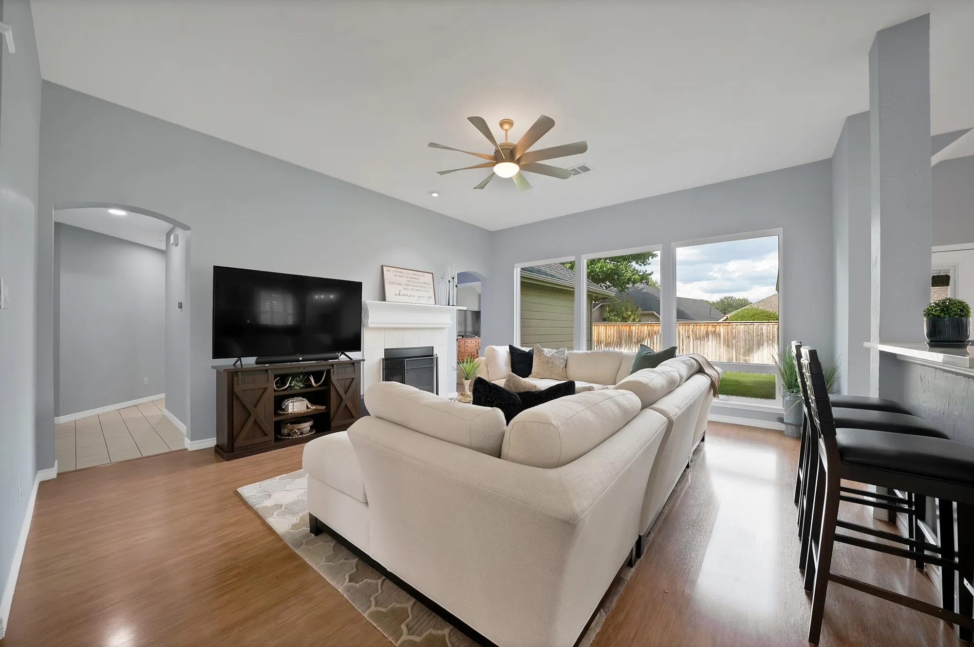 Wood-finish flooring, vaulted ceiling, white mantel, built-in fireplace, and large windows