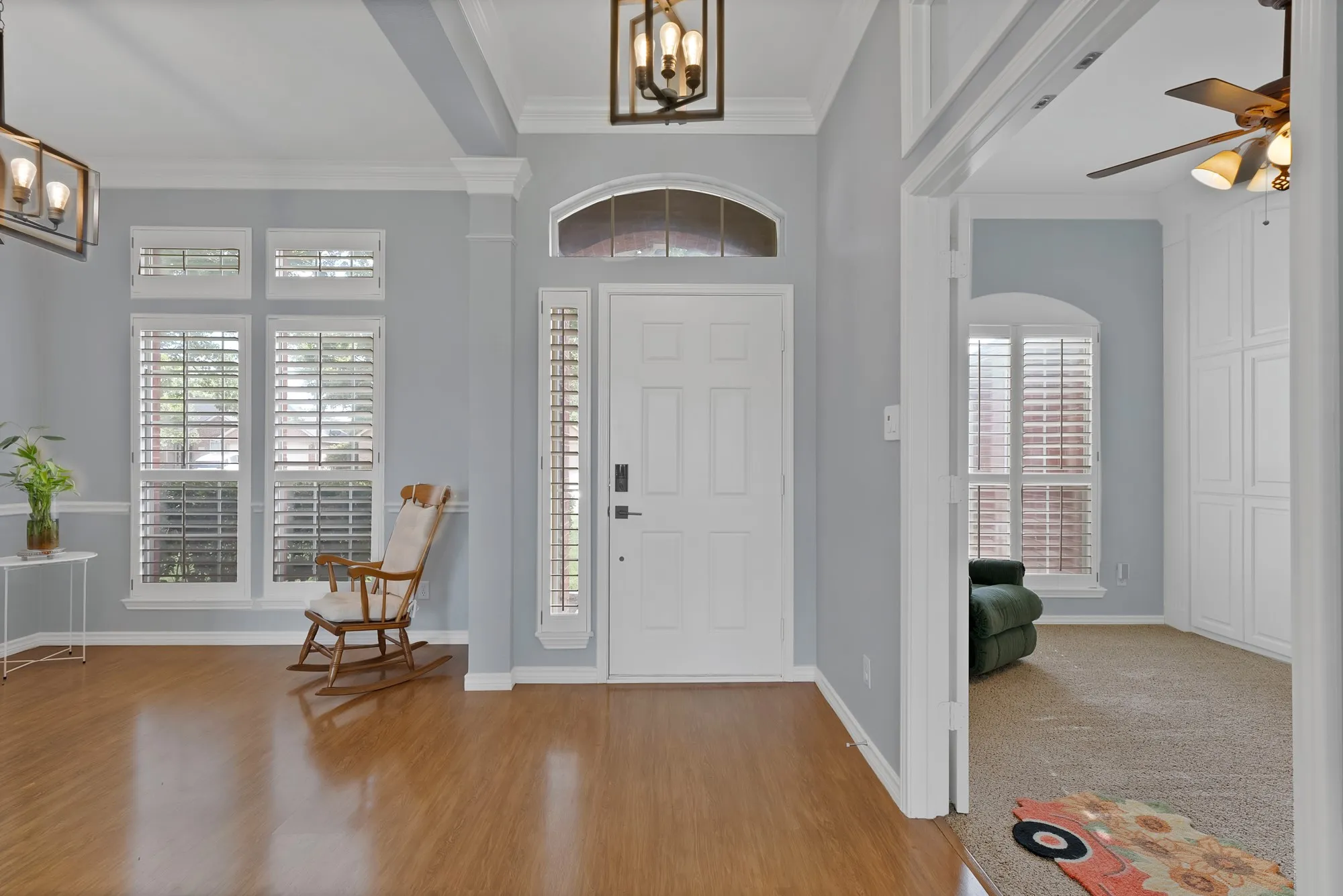 Entryway featuring wood-finish flooring, a paneled front door, an arched transom window, and a lantern-style chandelier