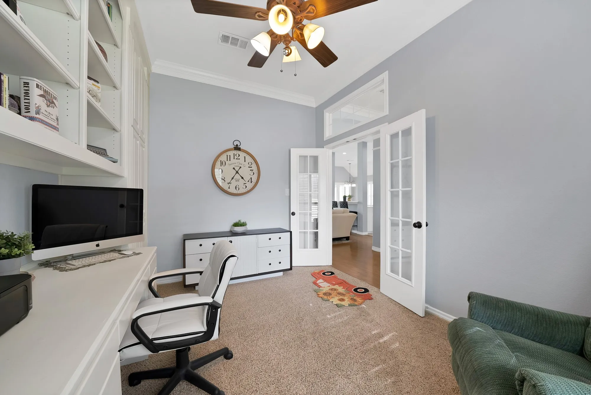 Built-in shelving, vaulted ceiling, ceiling fan, French doors with transom window, and neutral carpeting