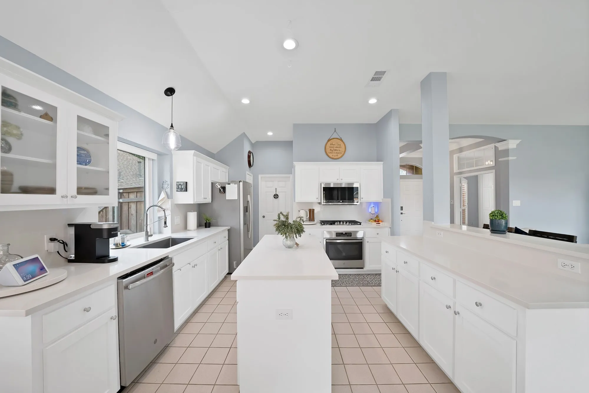 Kitchen featuring white cabinetry, stainless steel appliances, a center island, and tile flooring