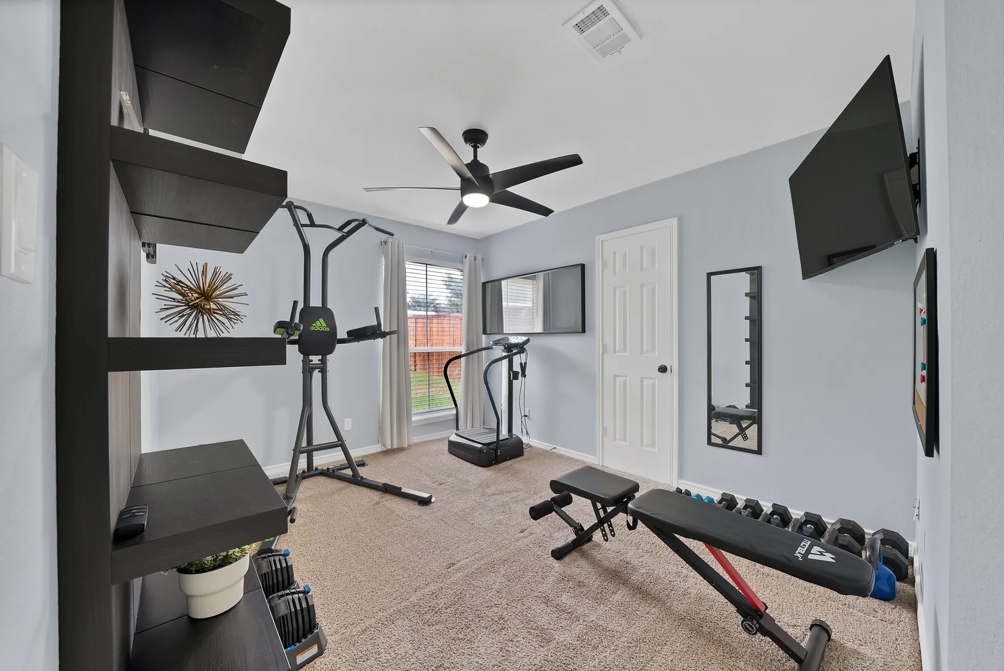 Carpeted room featuring a ceiling fan, a window with blinds, and built-in wall shelving