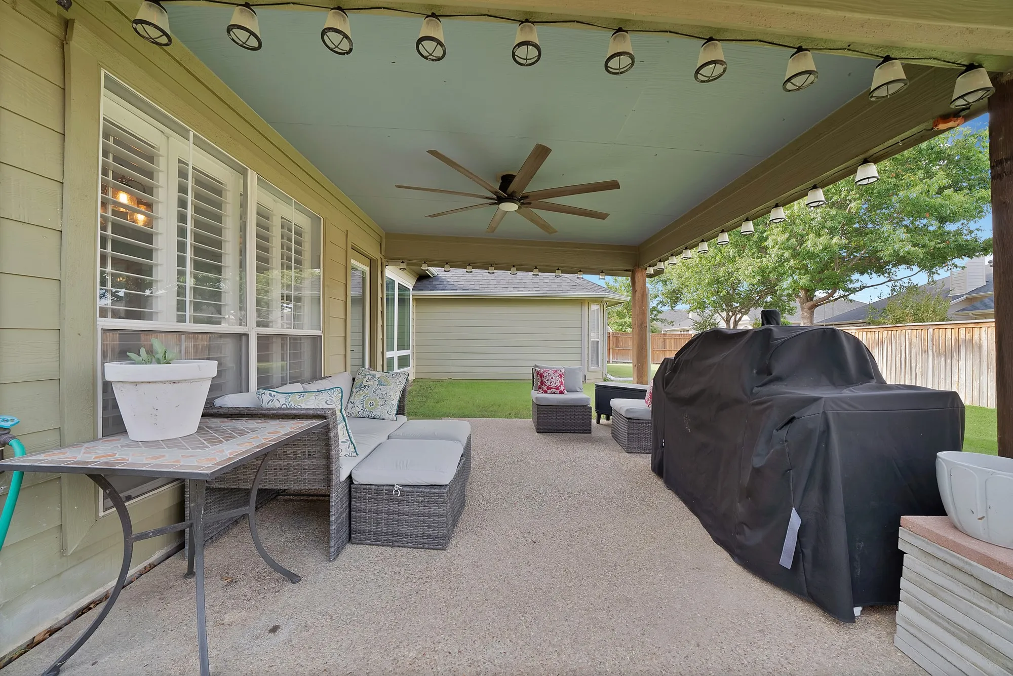 Covered patio with a ceiling fan, string lighting, and direct access to the interior