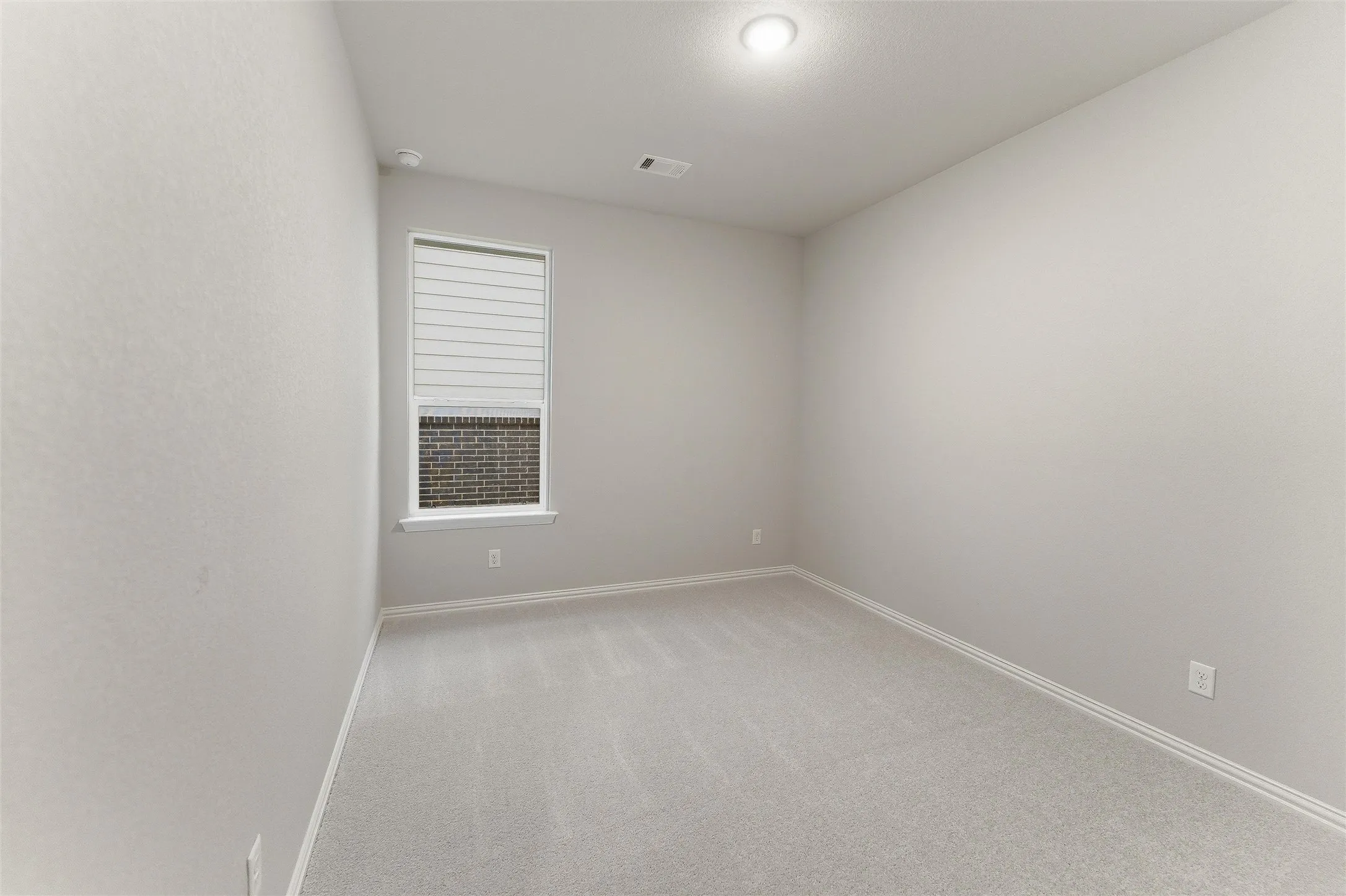 Carpeted room with neutral wall tones and a single window featuring horizontal blinds