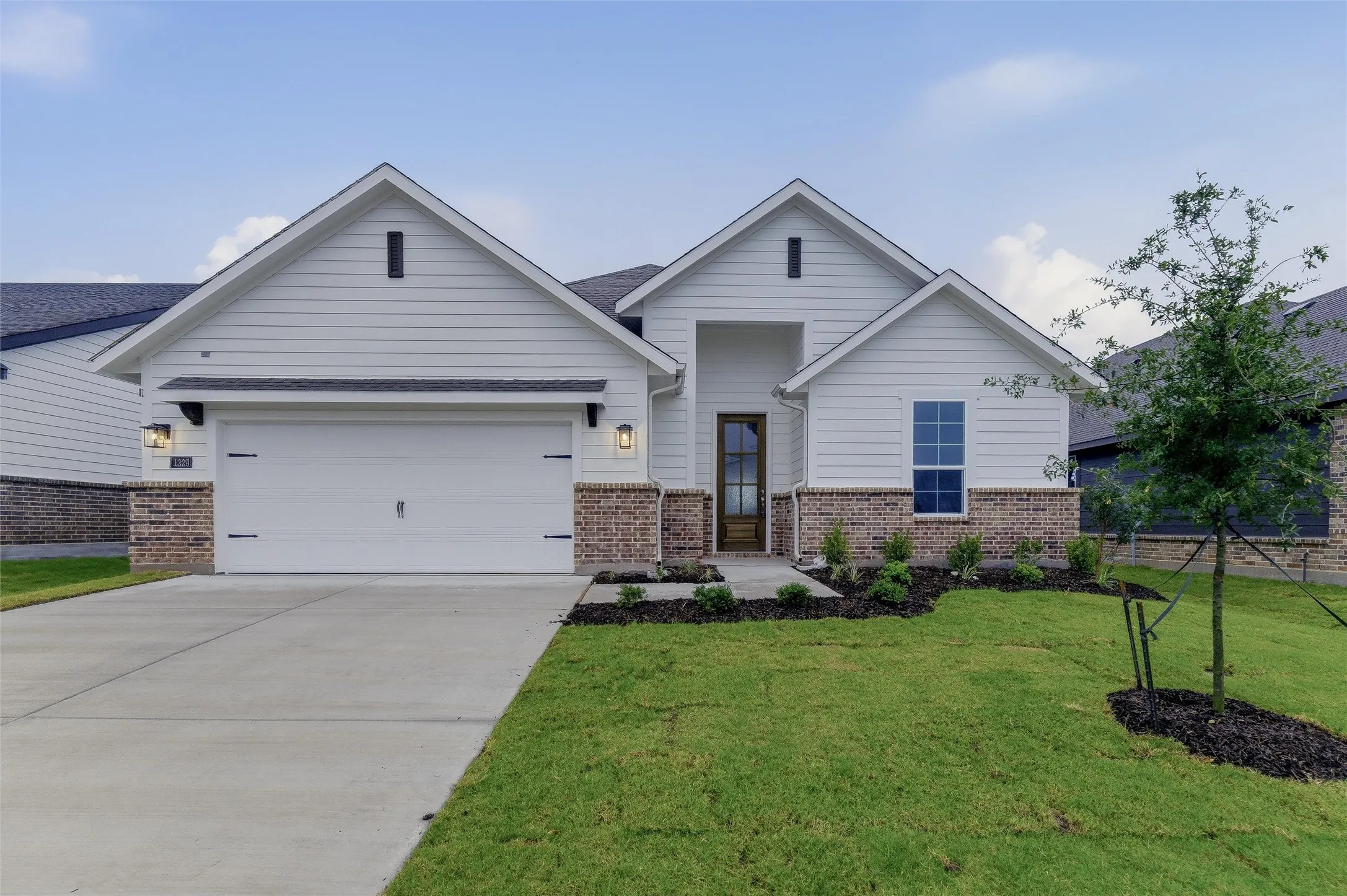 Contemporary facade featuring white horizontal siding and a brick-finish wainscot