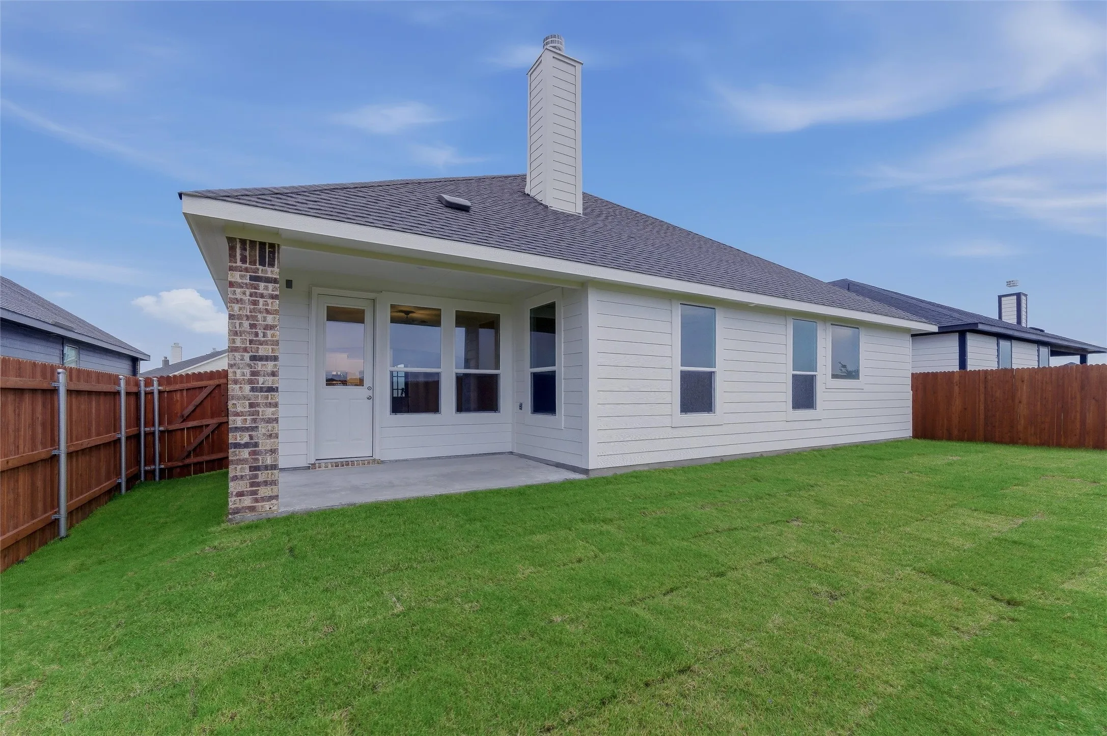 Expansive backyard with a covered concrete patio, new sod, and privacy fencing