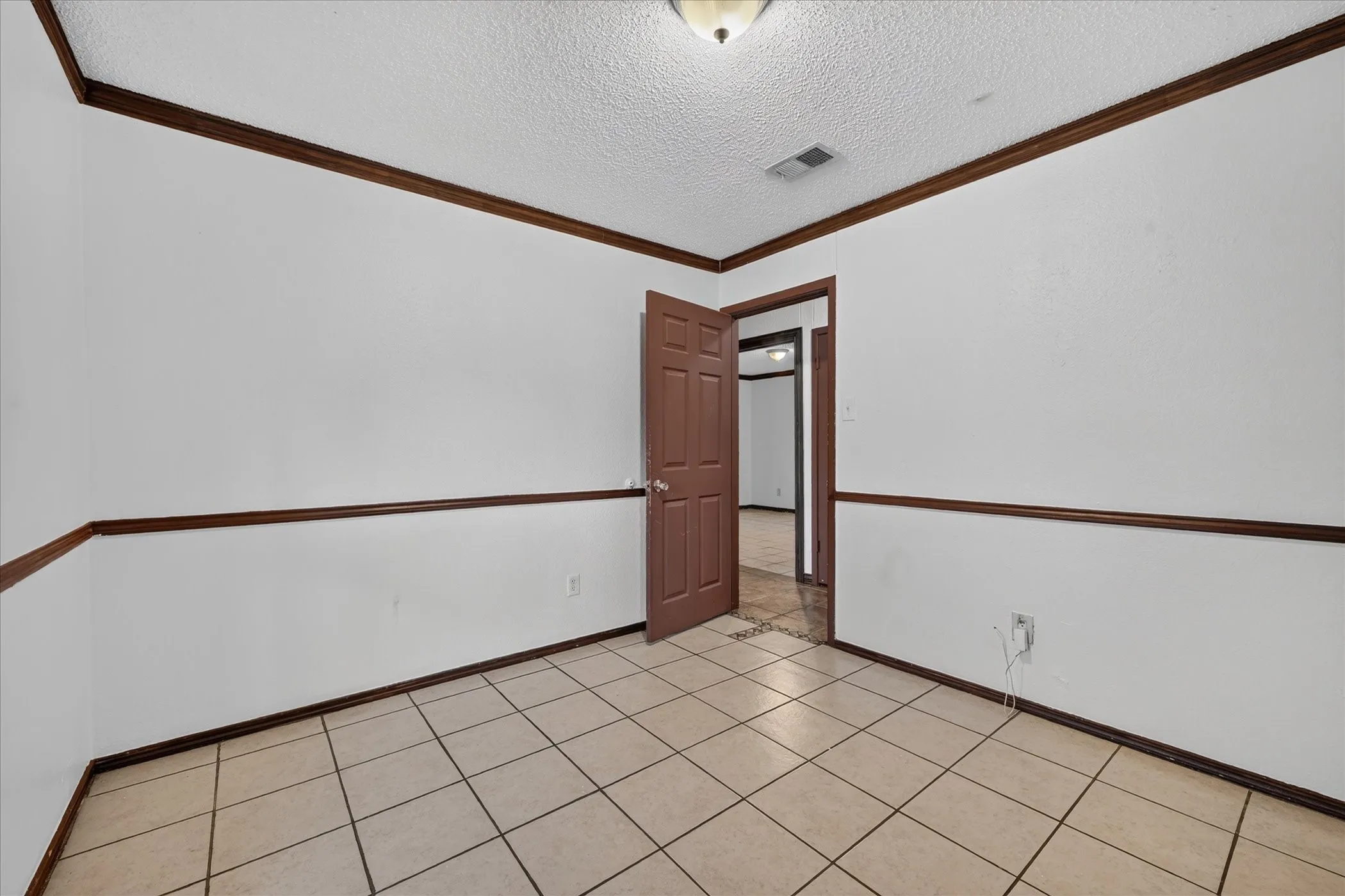 Tile flooring with a neutral finish, white walls, and dark wood trim