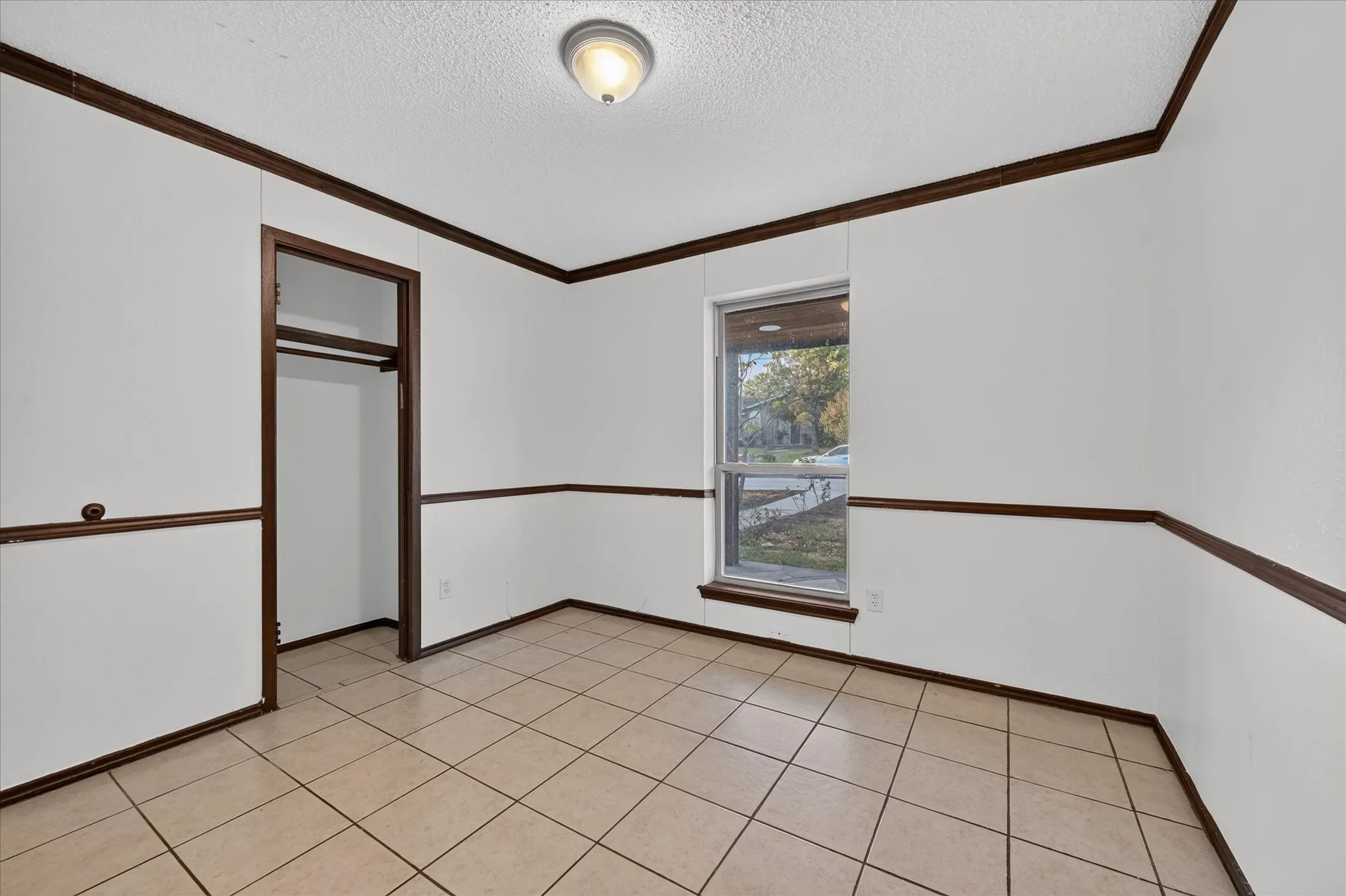 Tile flooring, white walls, dark wood trim, flush mount ceiling light, and a single window