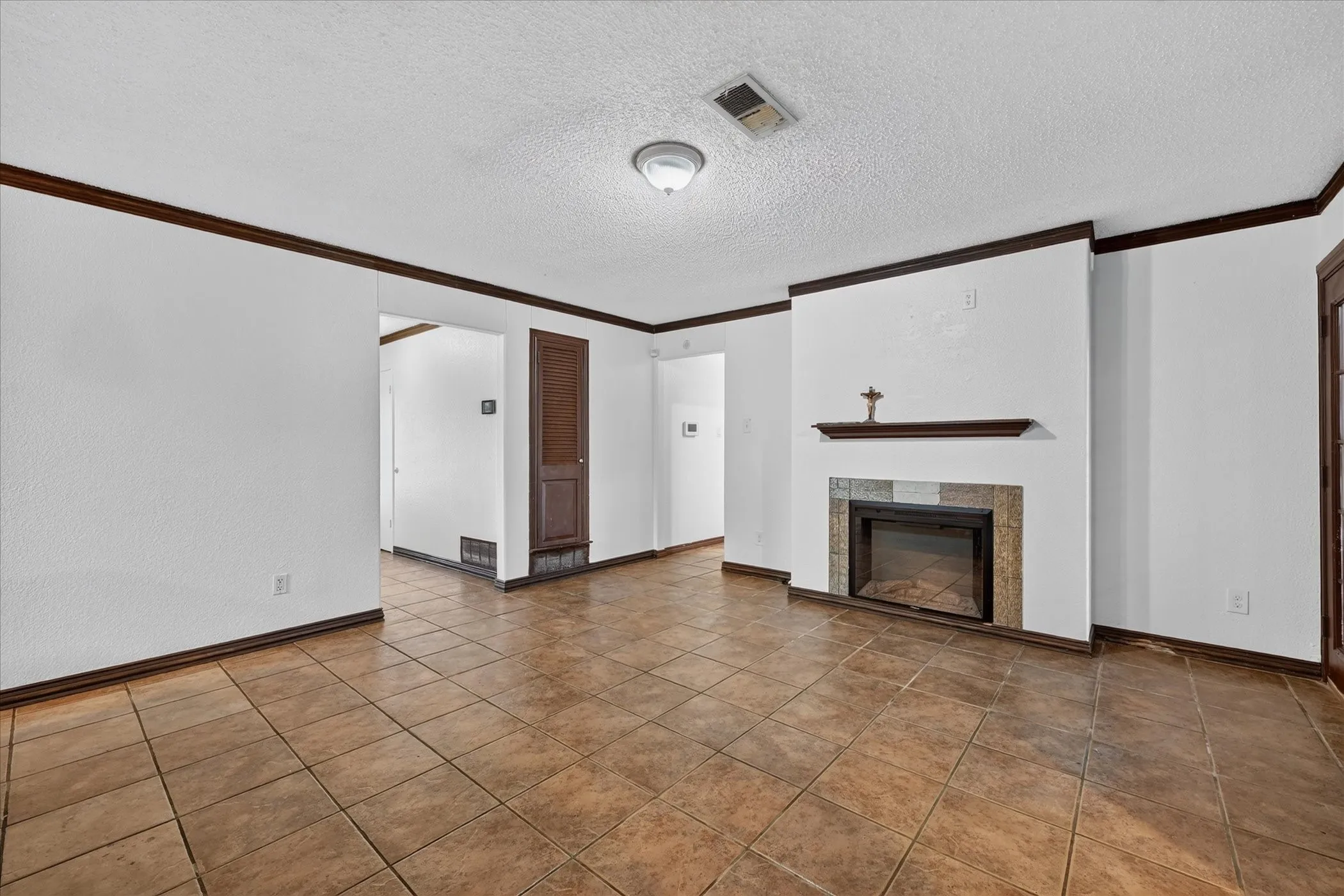 Tiled flooring throughout, featuring a fireplace with stone surround and wood mantle