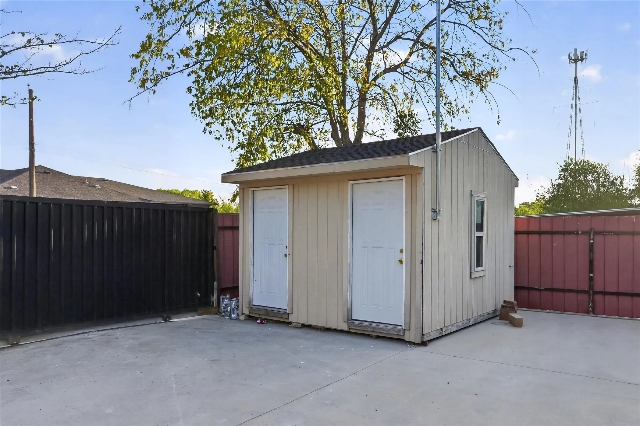 Detached storage building featuring two entry doors, vertical siding, a shingled roof, and a single window