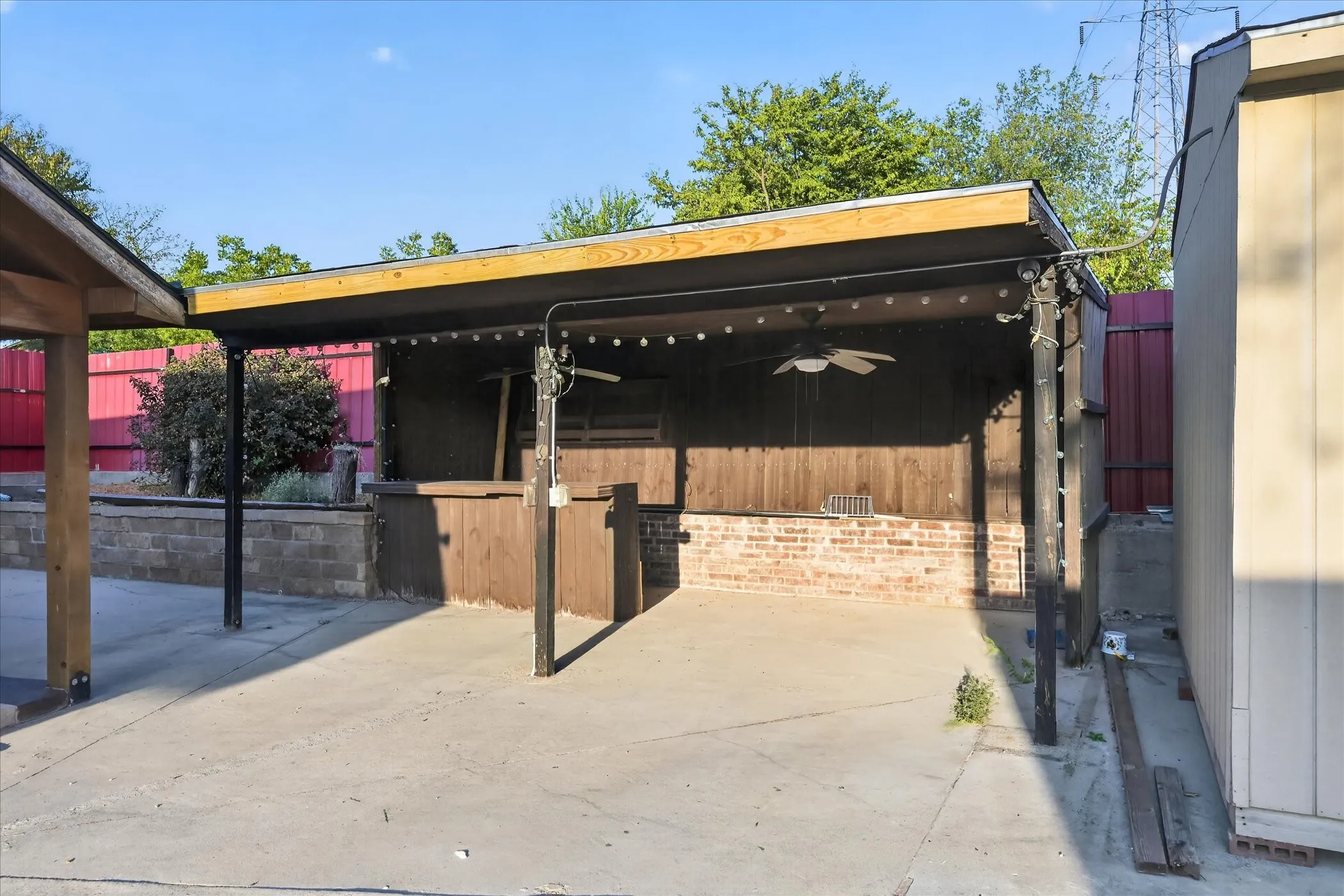 Covered patio featuring a built-in bar with brick accents, wood-finish paneling, and a ceiling fan