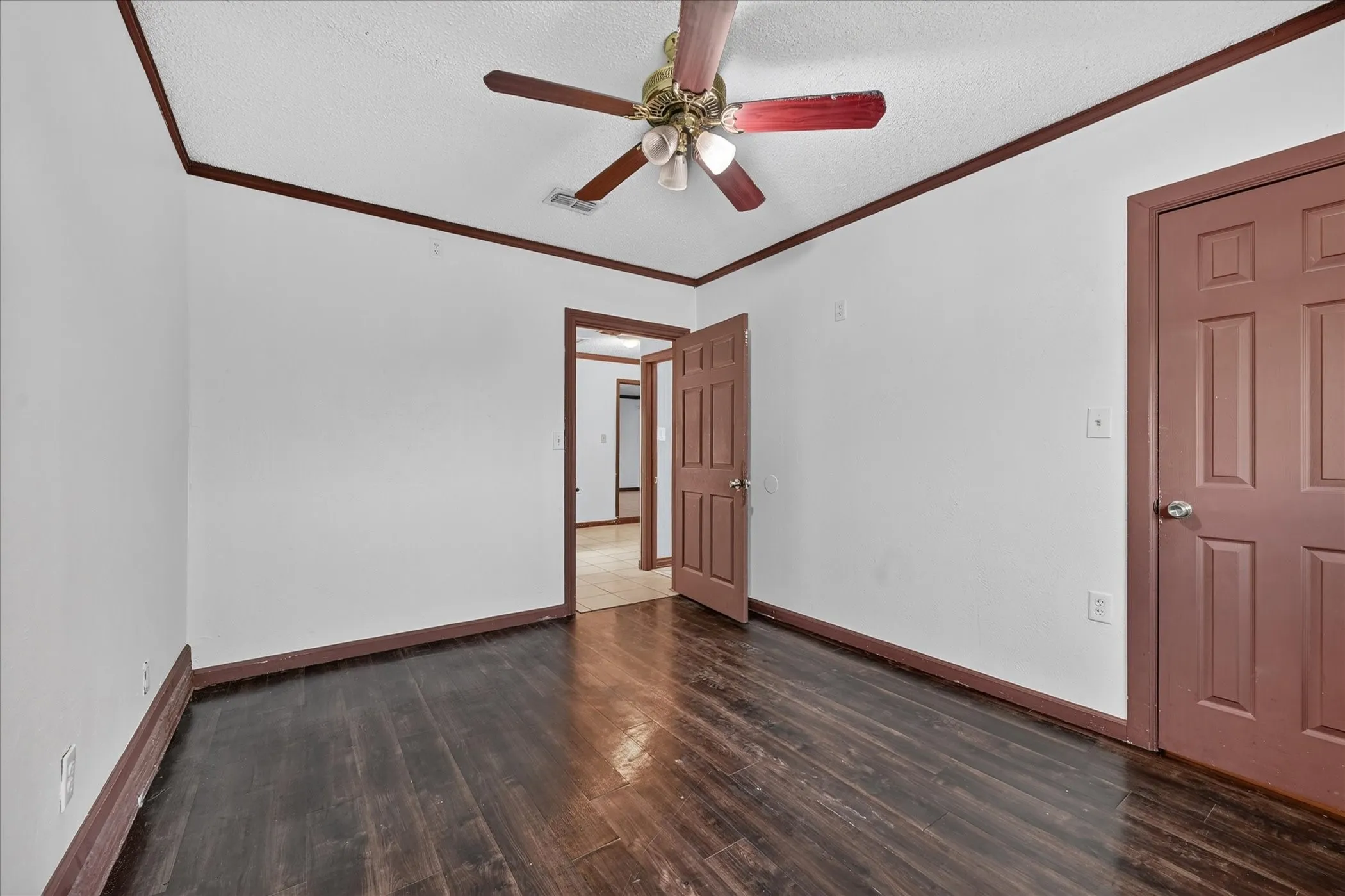 Dark wood-finish flooring, white walls, and a ceiling fan with light fixture
