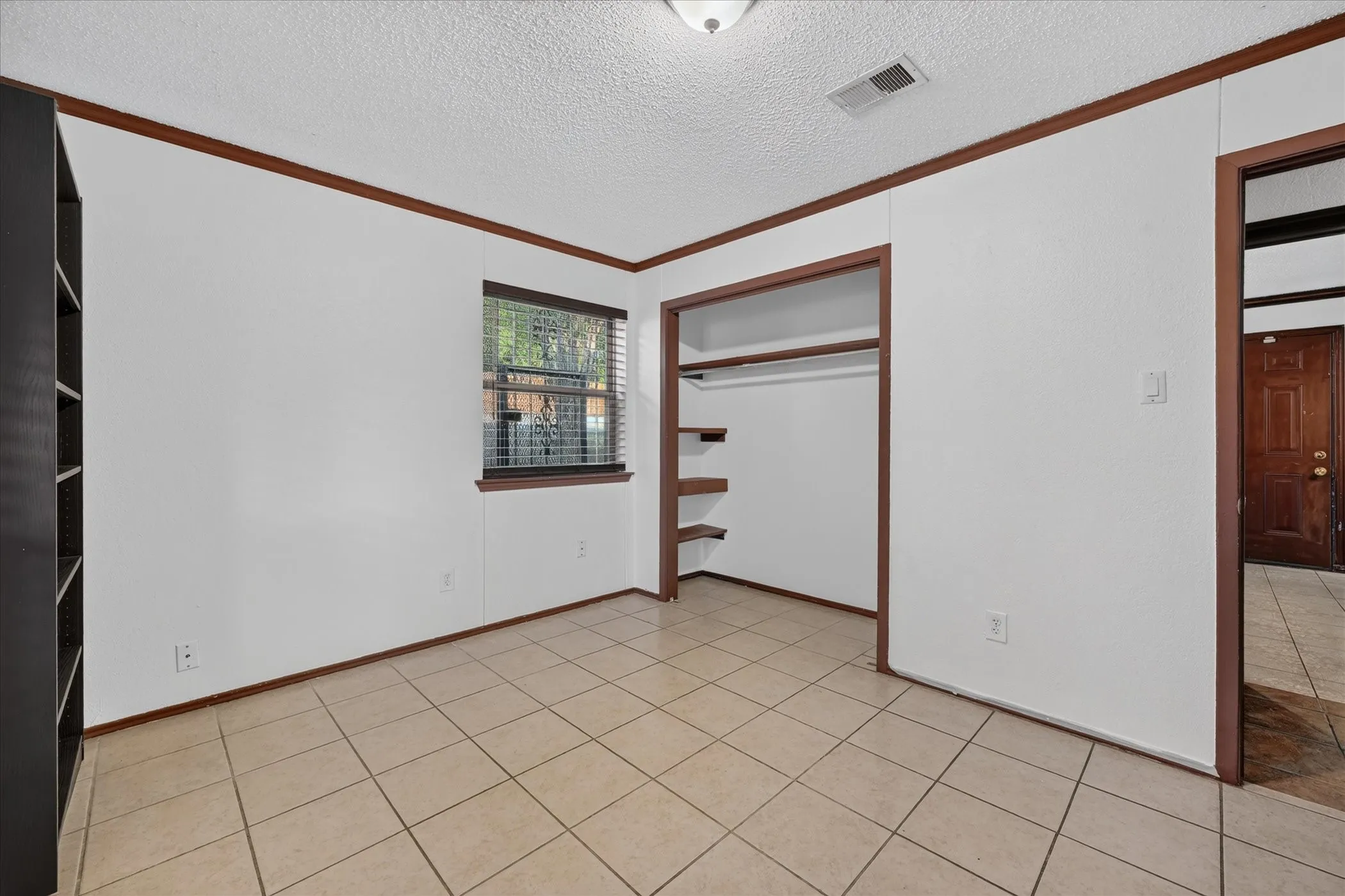 Tile flooring, wood-finish trim, window with blinds, and a closet with shelving and hanging rod