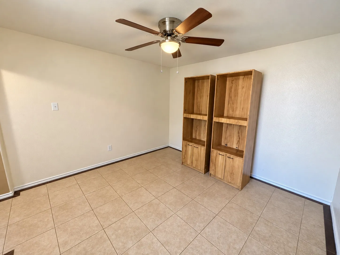 Ceiling fan with wood-finish blades, tile flooring, and light-toned walls