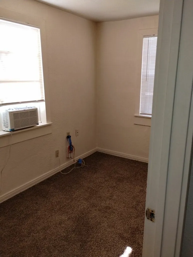 Carpeted room featuring two windows with horizontal blinds