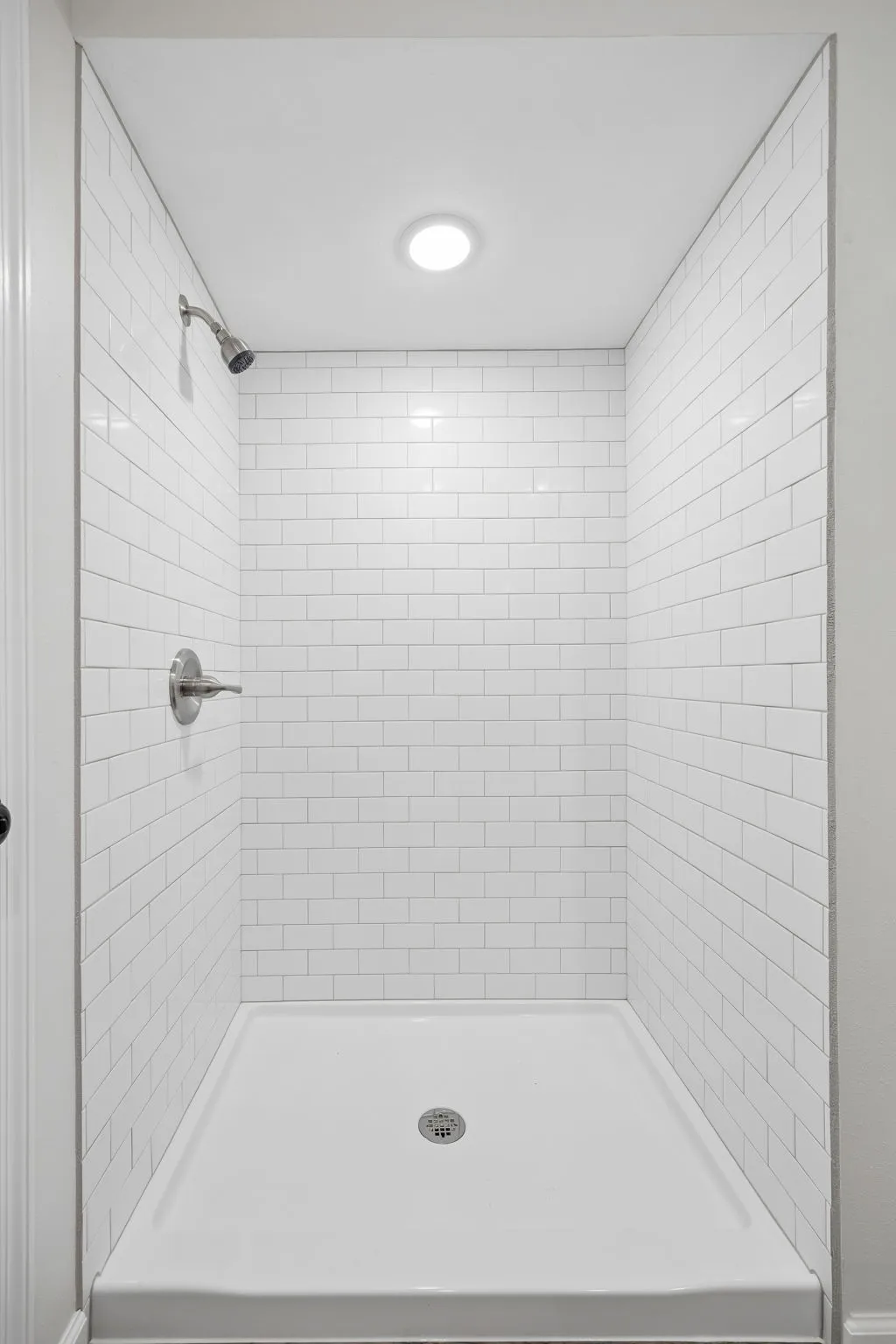 Shower with white subway tile surround, recessed lighting, and a chrome shower head and fixtures