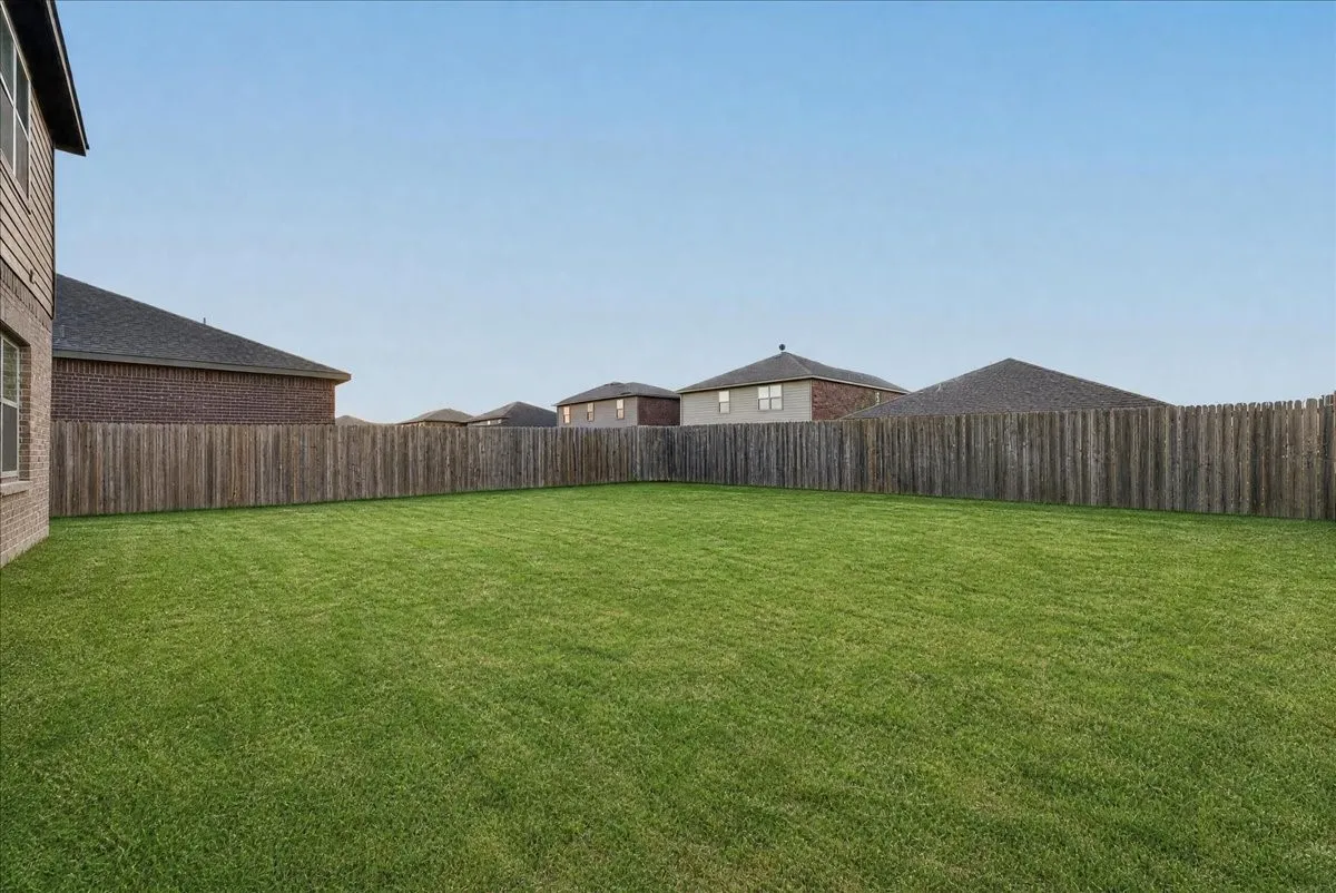 Expansive green lawn with a full privacy fence