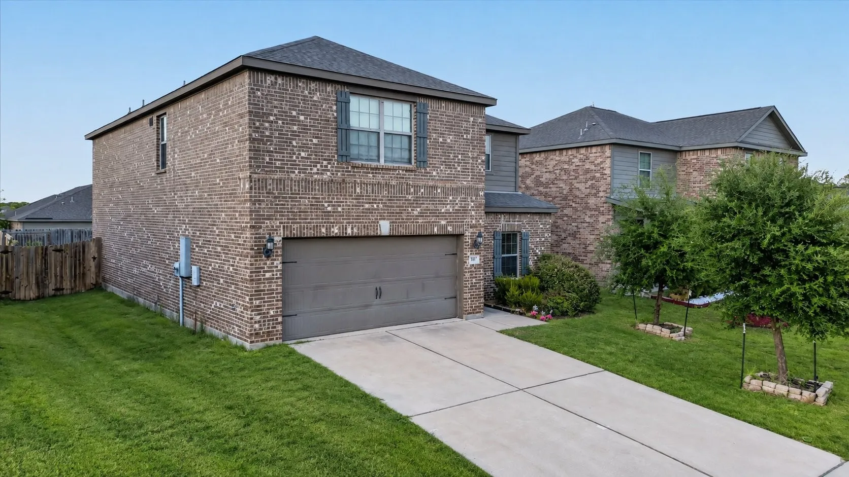 Brick exterior with gray siding accents, attached garage, concrete driveway, and front landscaping