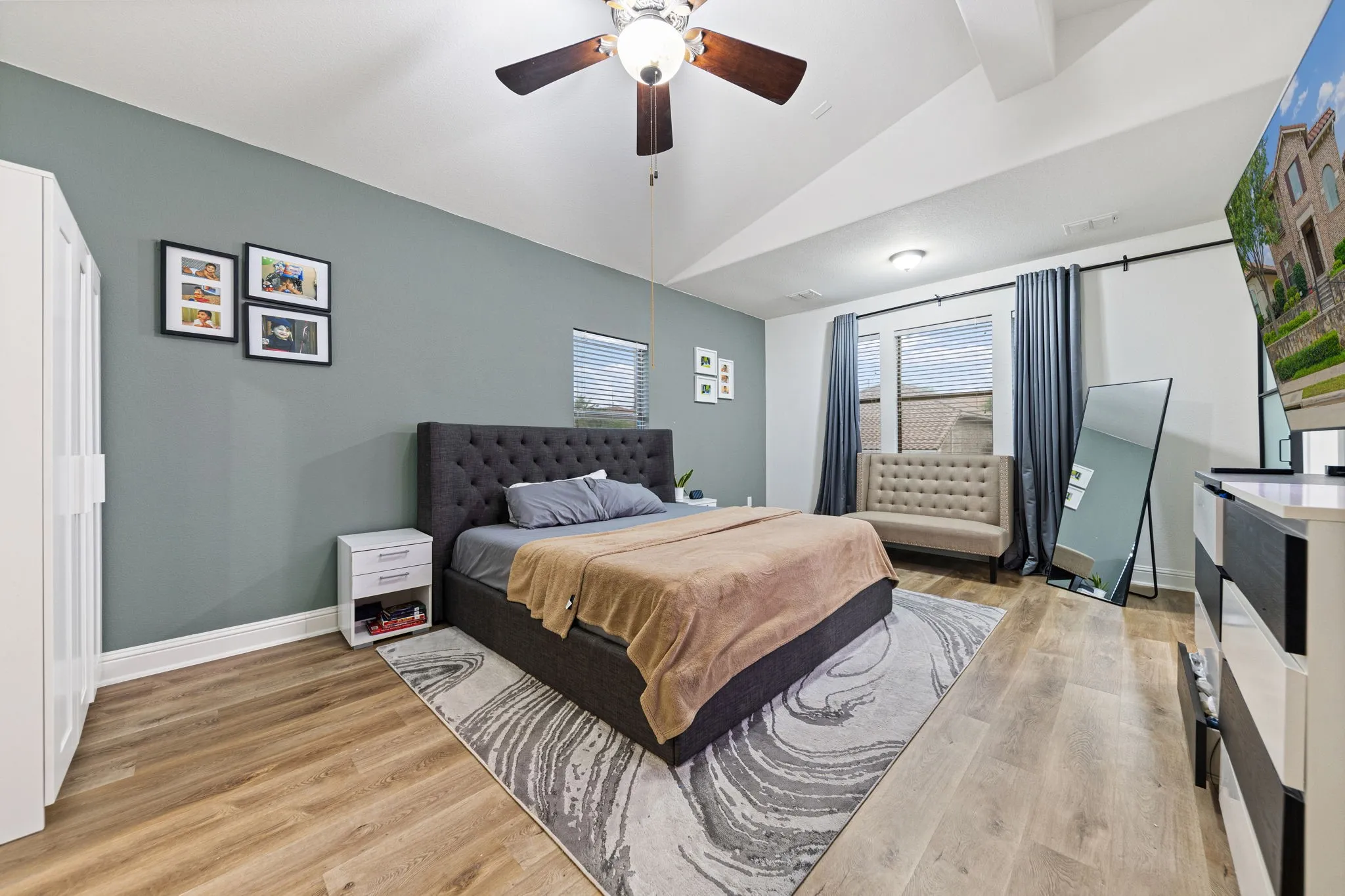 Vaulted ceiling with a ceiling fan, wood-finish flooring, and white trim