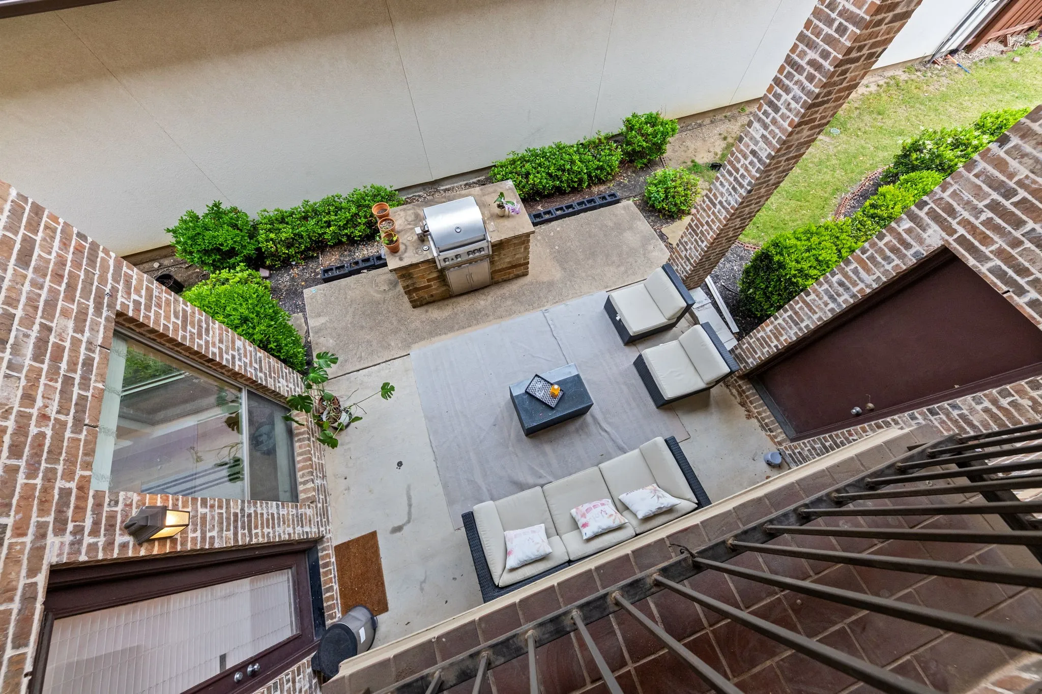 Outdoor patio with concrete and tile flooring, brick walls, and an integrated grilling station