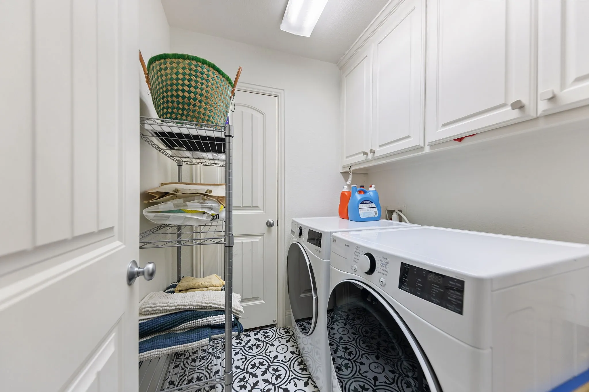 White shaker-style cabinetry, patterned tile flooring, and a flush-mount overhead light fixture