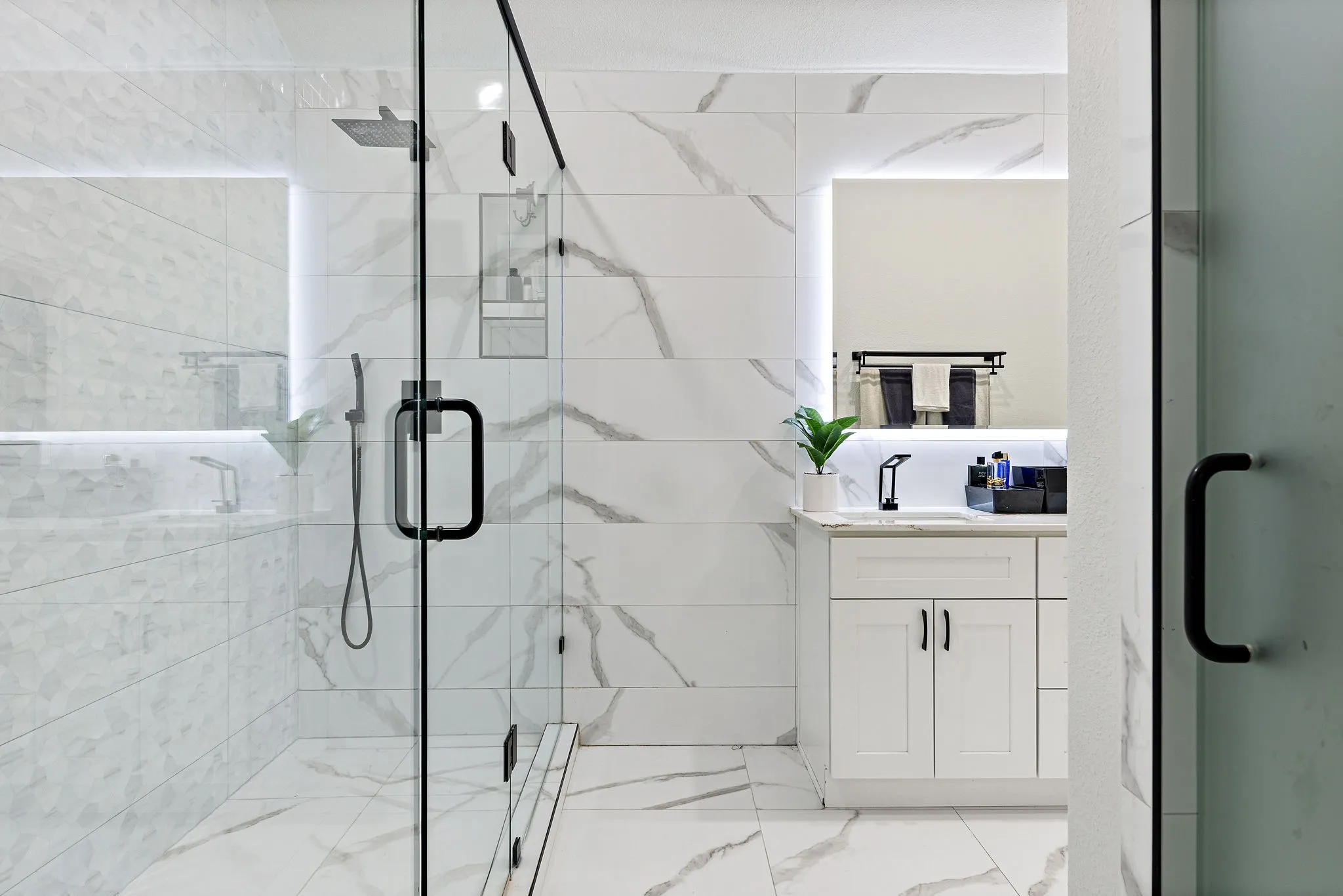 Glass-enclosed shower with a rainfall showerhead and a built-in recessed shelf