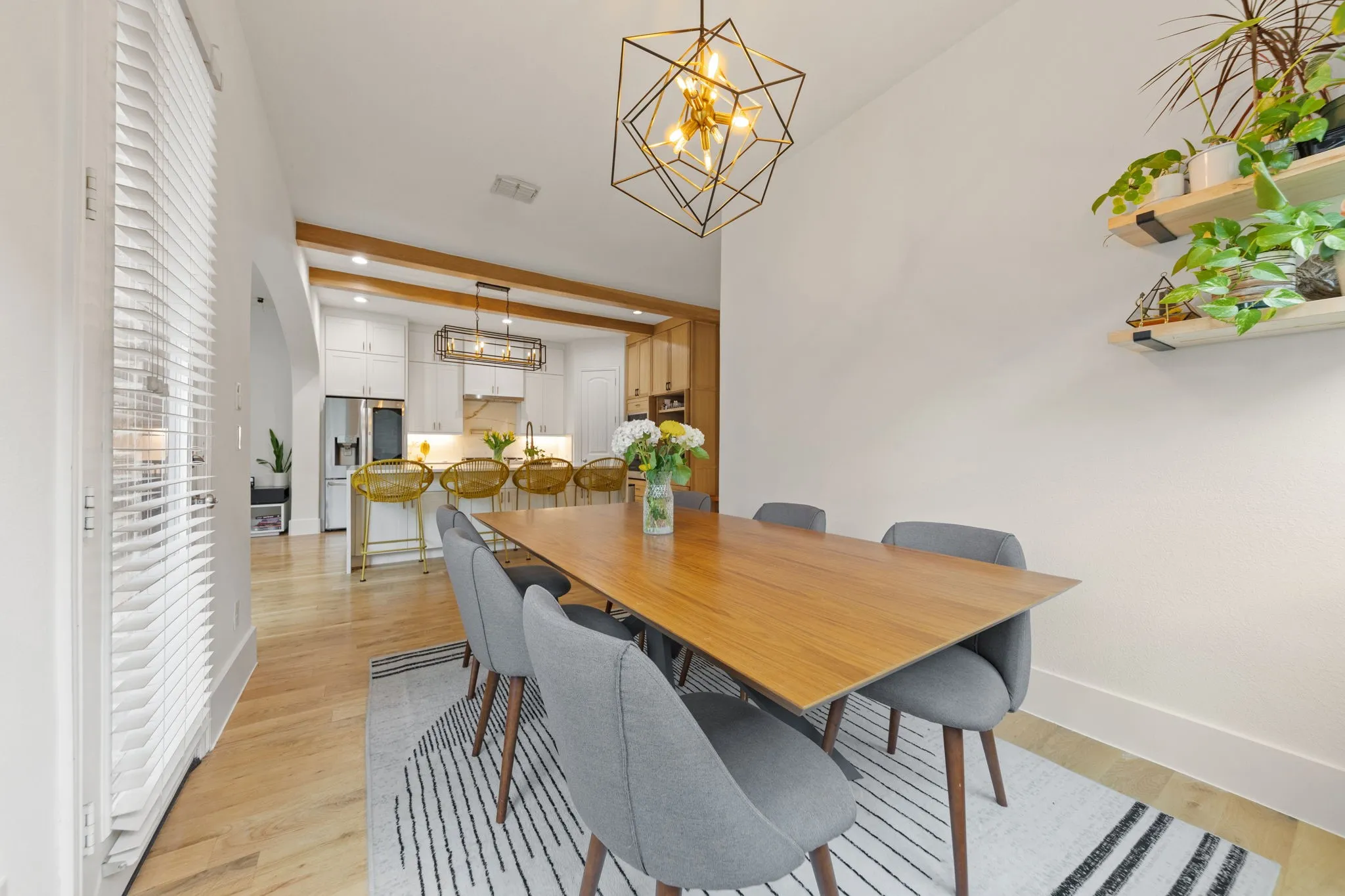 Open-concept dining area with wood-finish flooring, a contemporary geometric chandelier, and built-in shelving