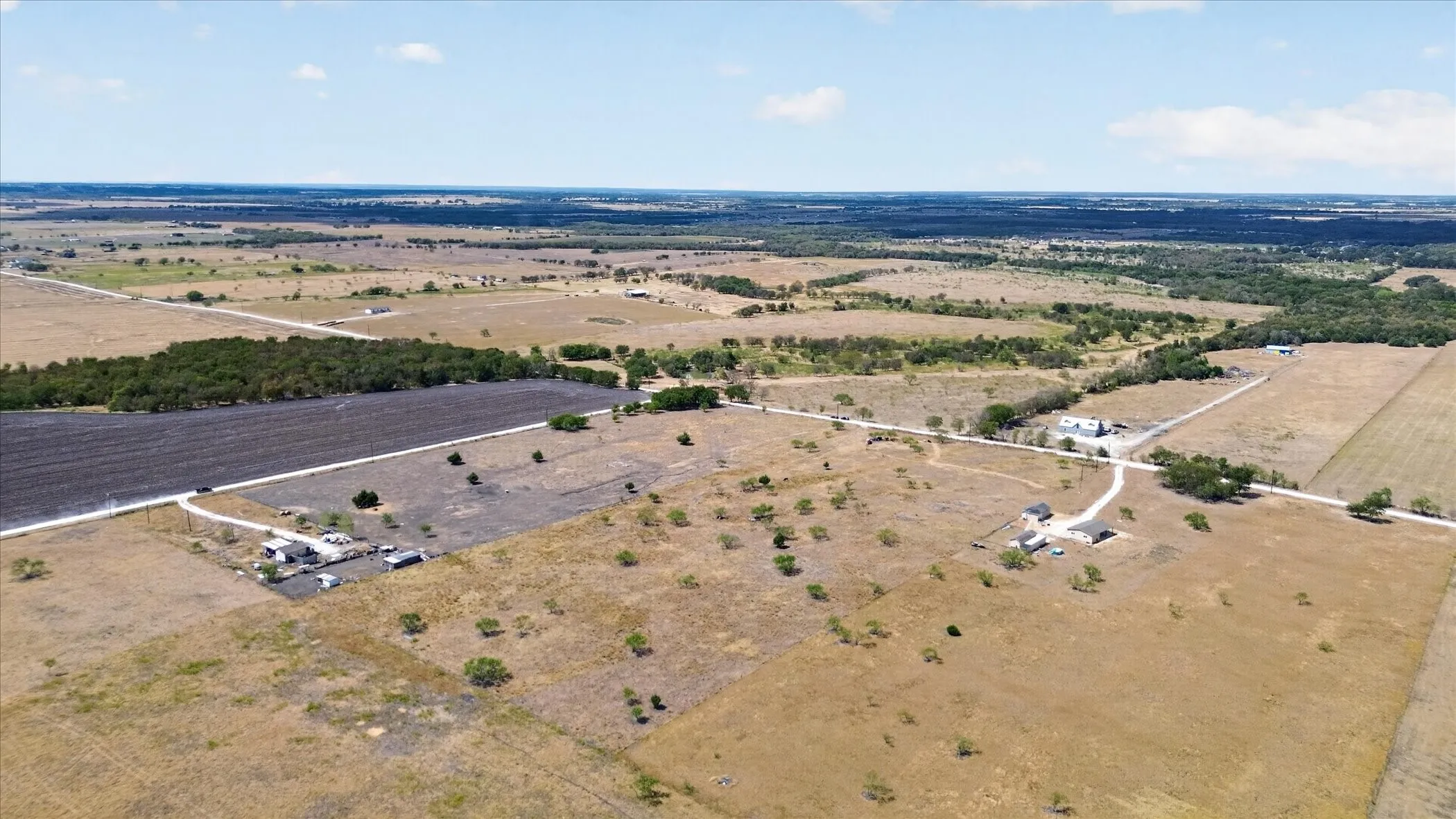 Expansive rural landscape featuring a mix of open fields, wooded areas, and agricultural land