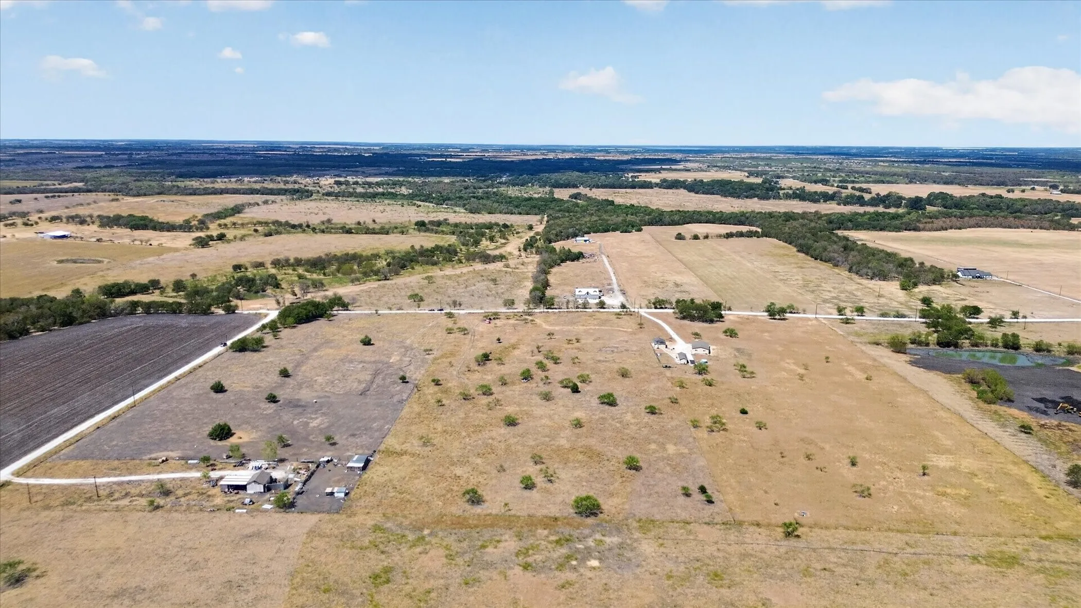 Extensive acreage featuring multiple structures, cleared land, and natural water features