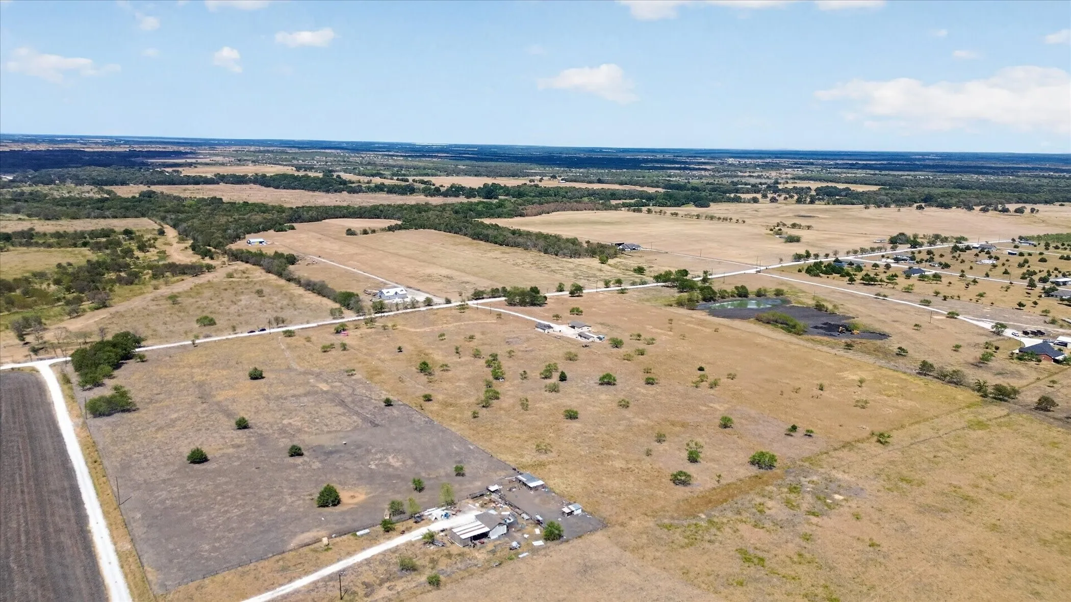 Expansive rural landscape with established roadways and scattered residential structures