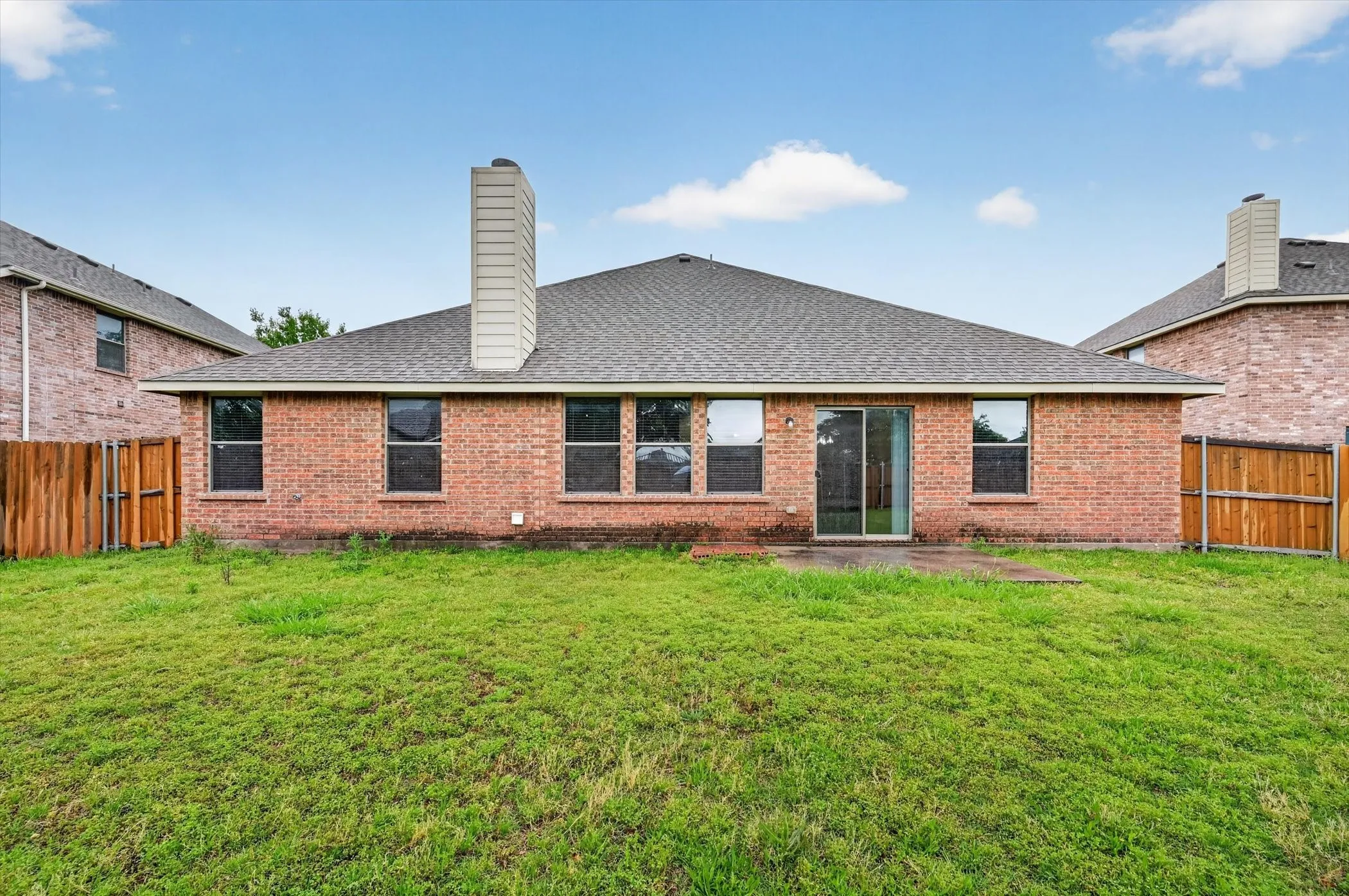 Brick exterior with a gray shingle roof and a prominent chimney