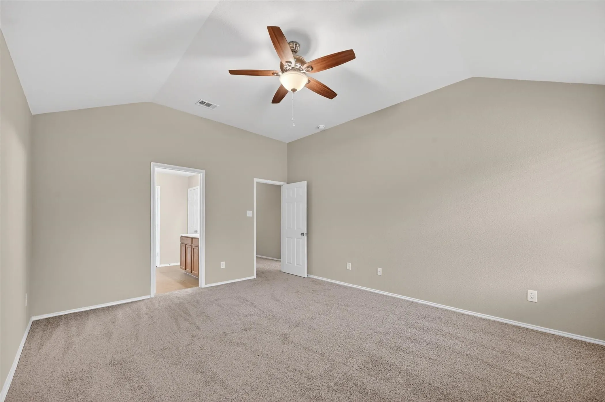 Vaulted ceiling with an attached ceiling fan, neutral-toned walls, and carpet flooring