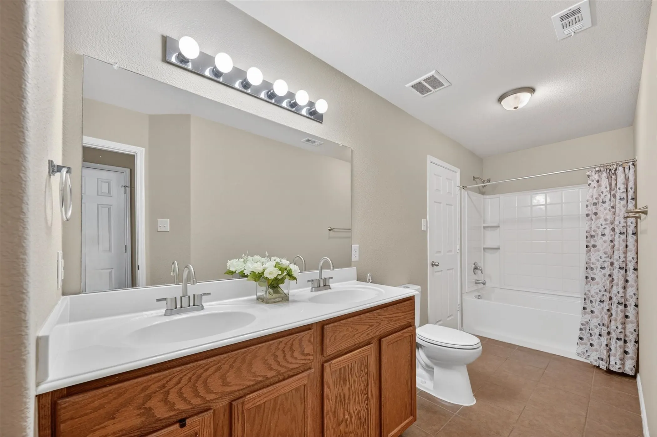 Dual vanity with integrated sinks, wood-finish cabinetry, and a full-width mirror