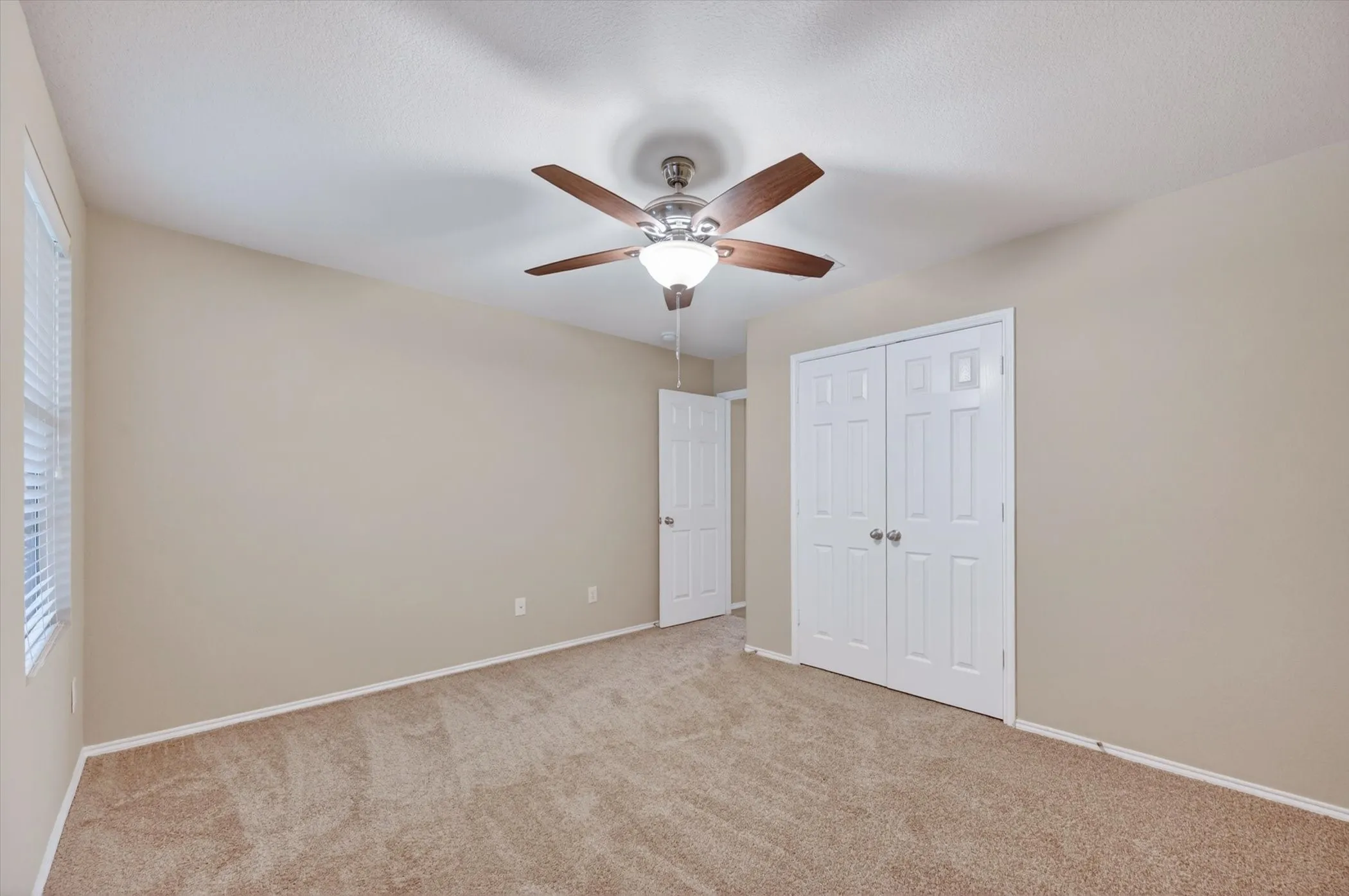 Carpeted flooring, vaulted ceiling, ceiling fan with light, white bi-fold closet doors, and window with blinds