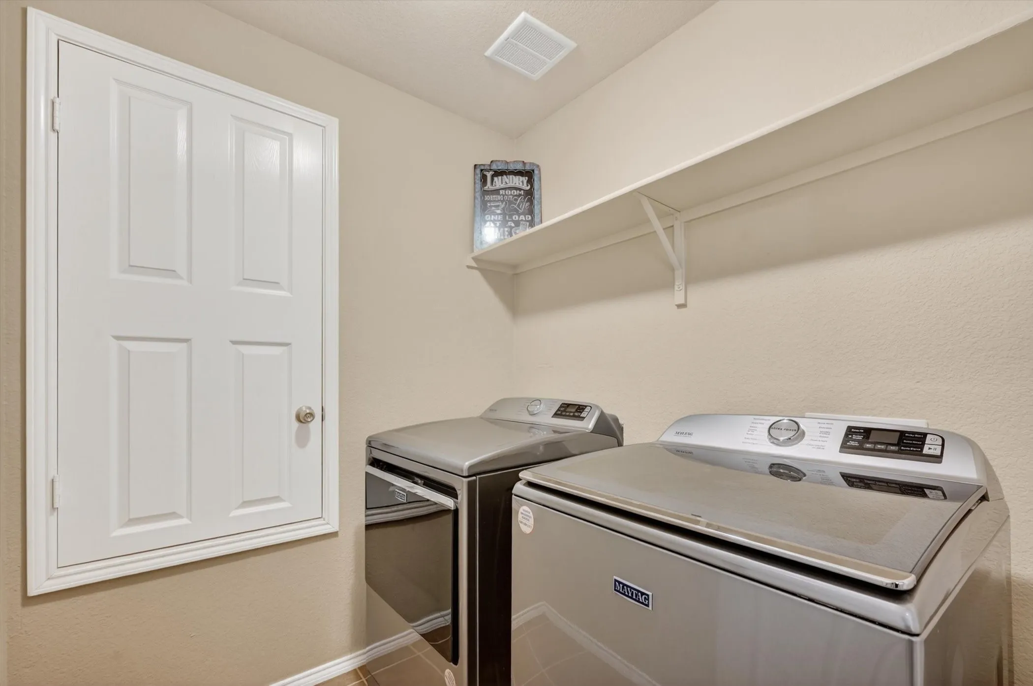 Utility space featuring a single white shelf and a panel-style door
