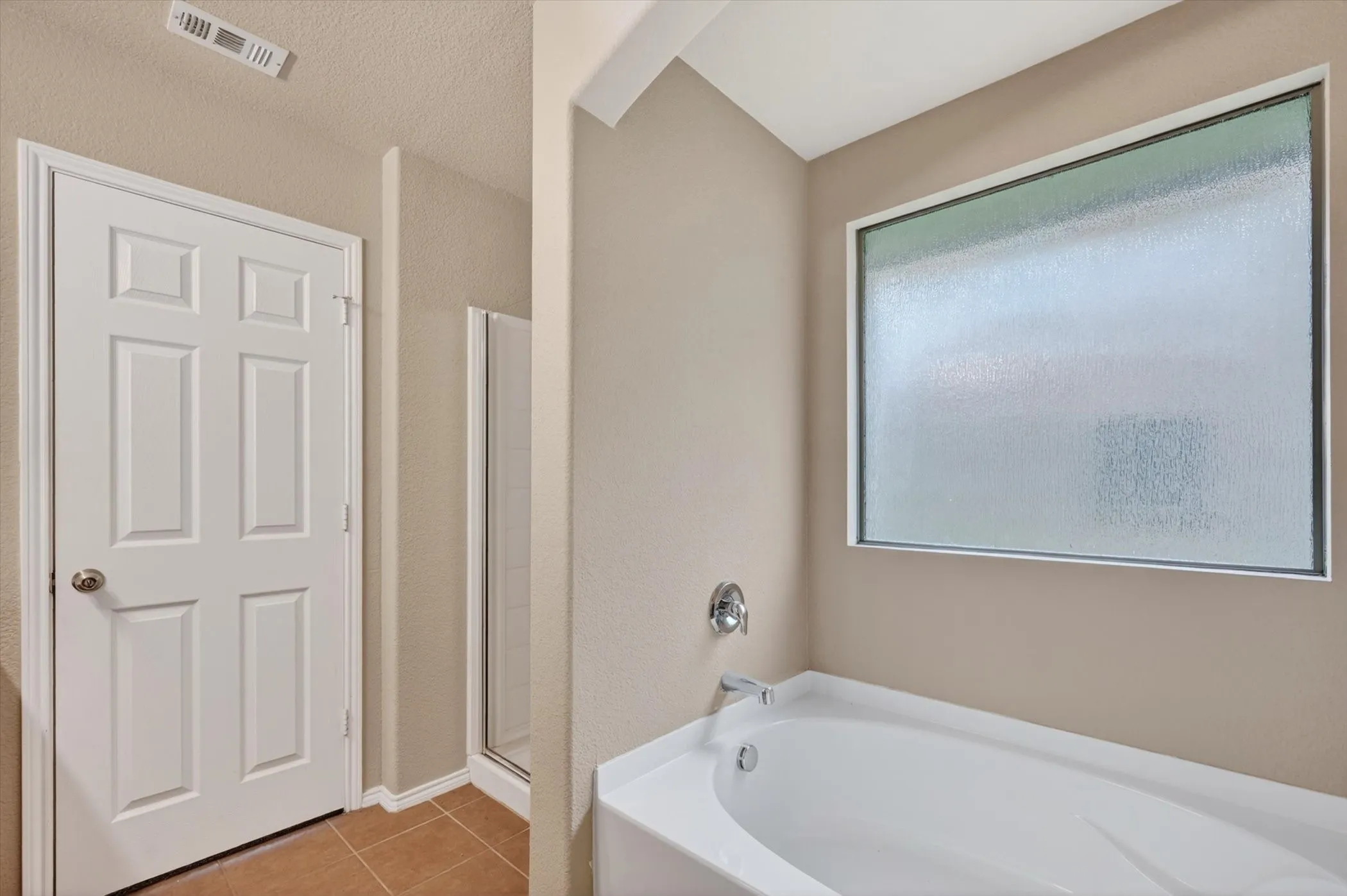 White soaking tub with chrome fixtures and privacy window