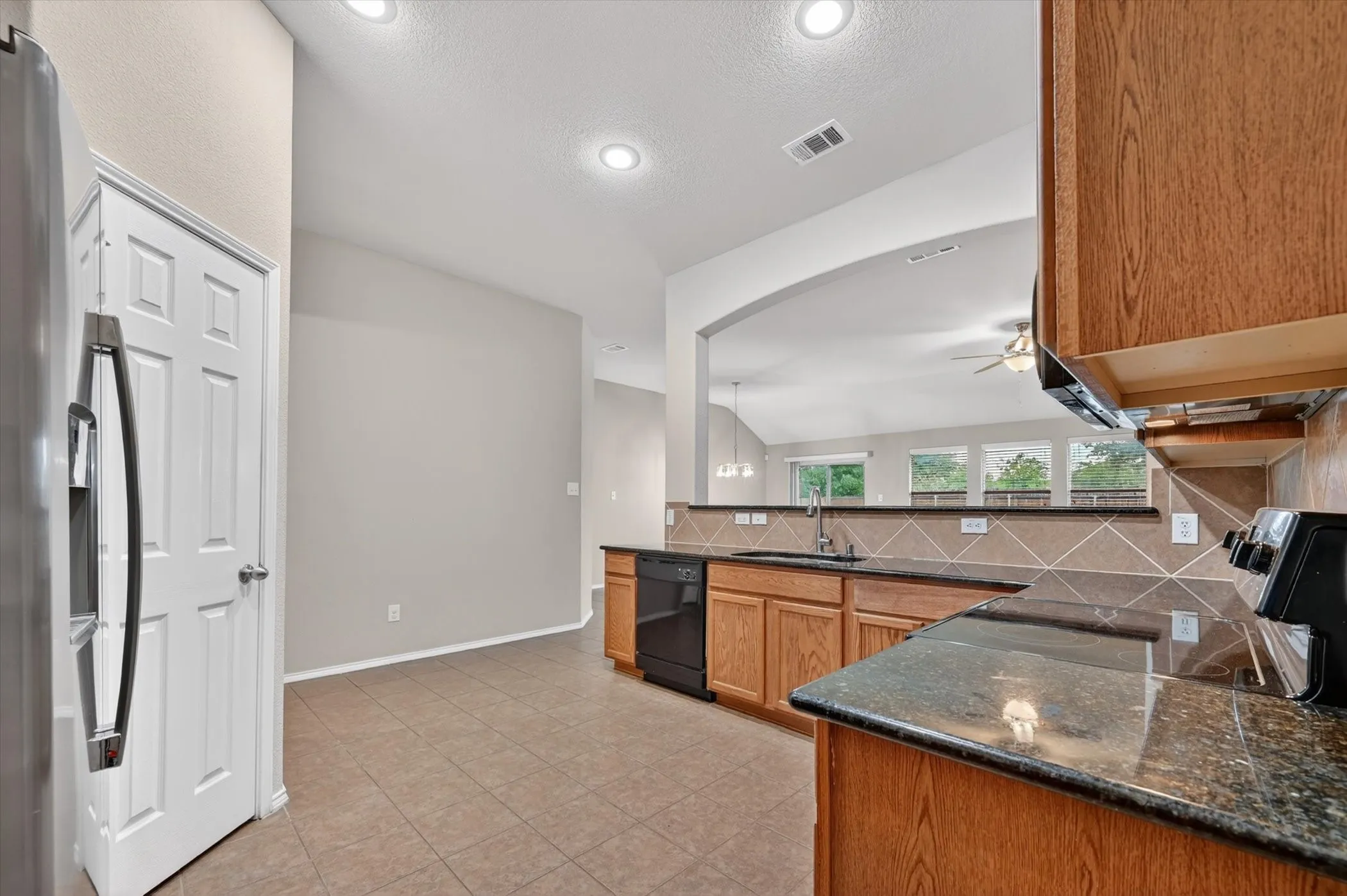 Kitchen featuring wood cabinetry, dark countertops, a tiled backsplash, and recessed lighting