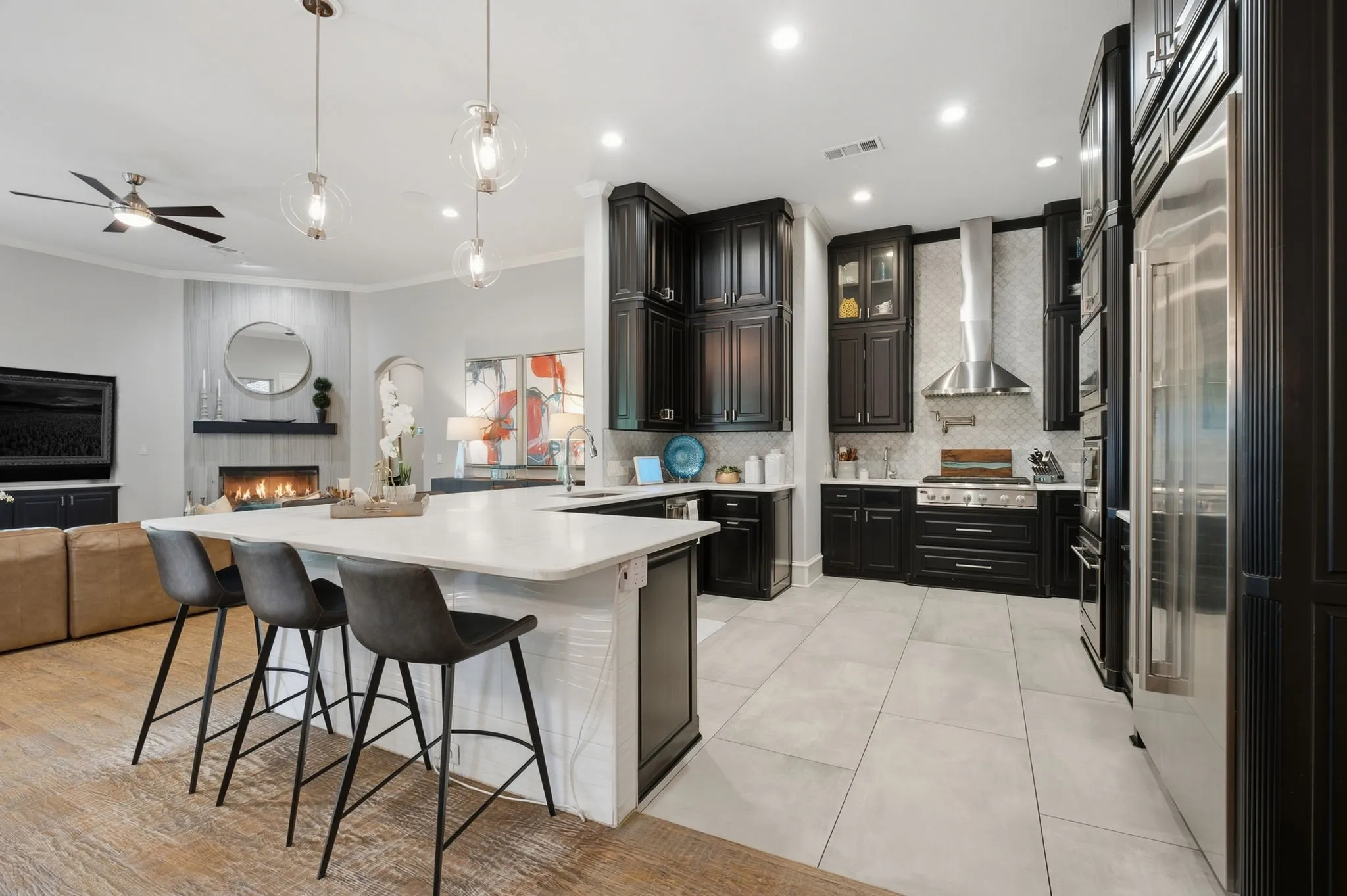 Three designer pendant fixtures elegantly illuminate the bar seating and enhance the kitchen’s contemporary aesthetic.
