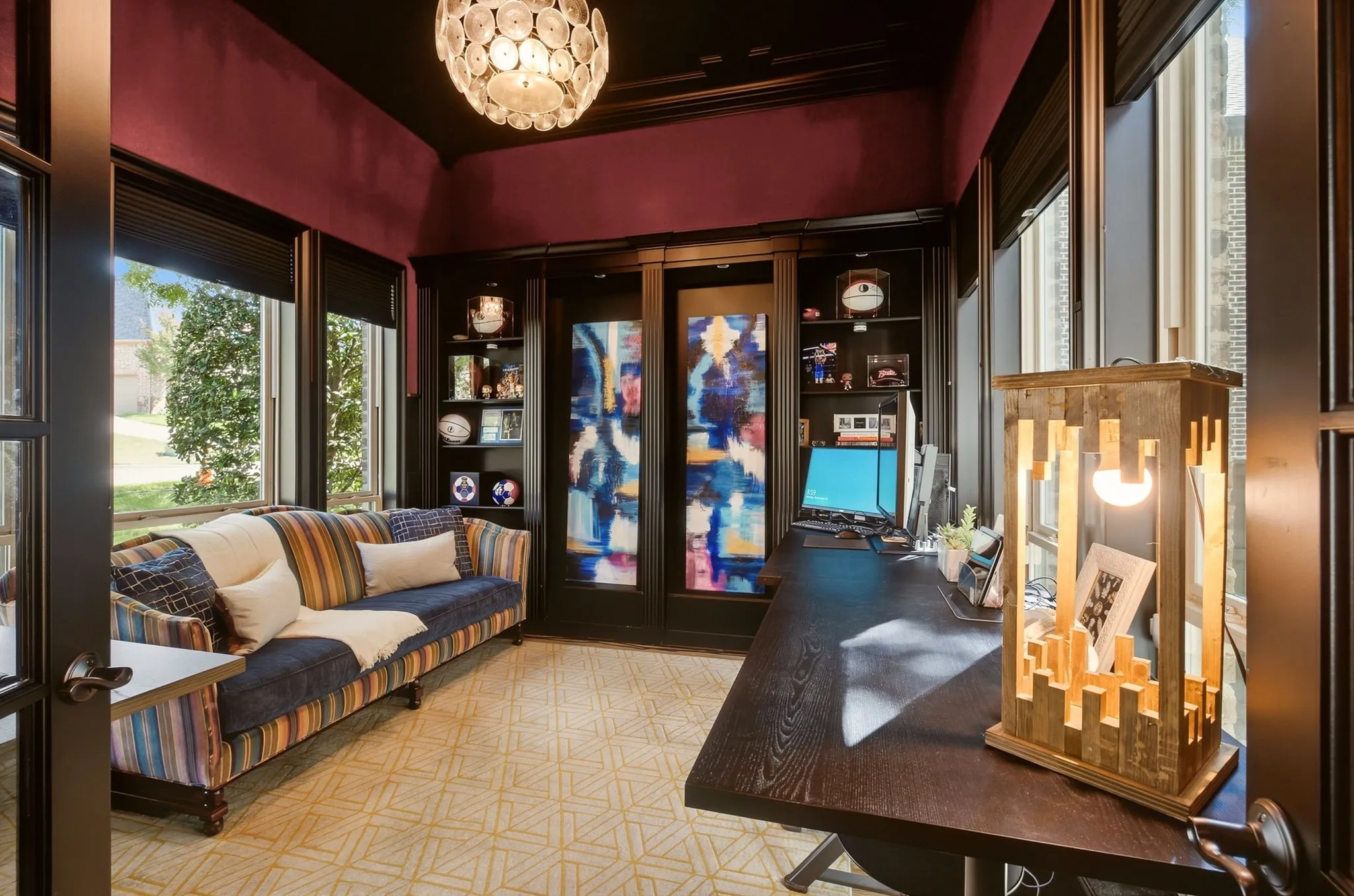 The executive study is accessed through glass-paneled French doors and showcases custom built-in shelving with undermount  lighting, and rich, dark-wood millwork throughout.